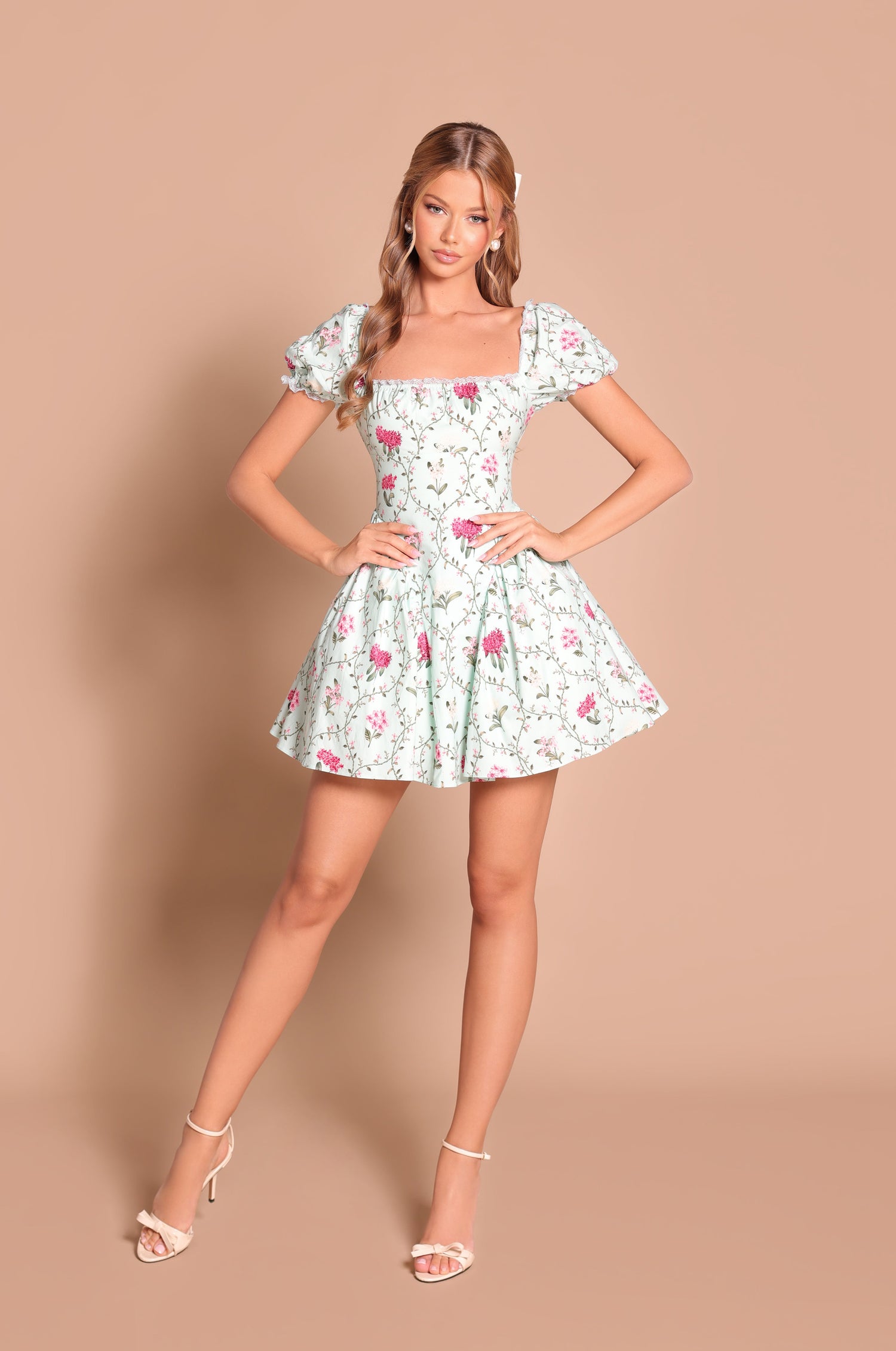 A woman stands against a beige background wearing the Rosabella mint green short casual dress and white high-heeled sandals.