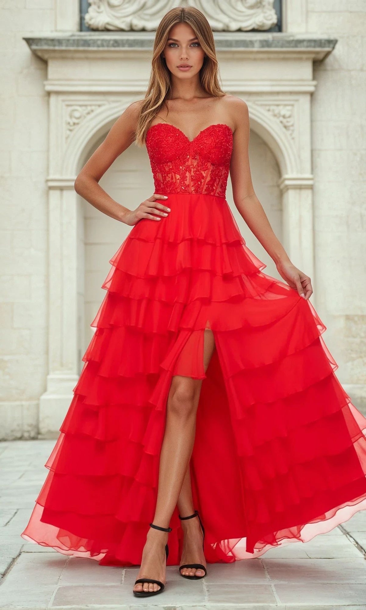 Woman wearing a red tiered a-line floor-length dress with a white architectural background
