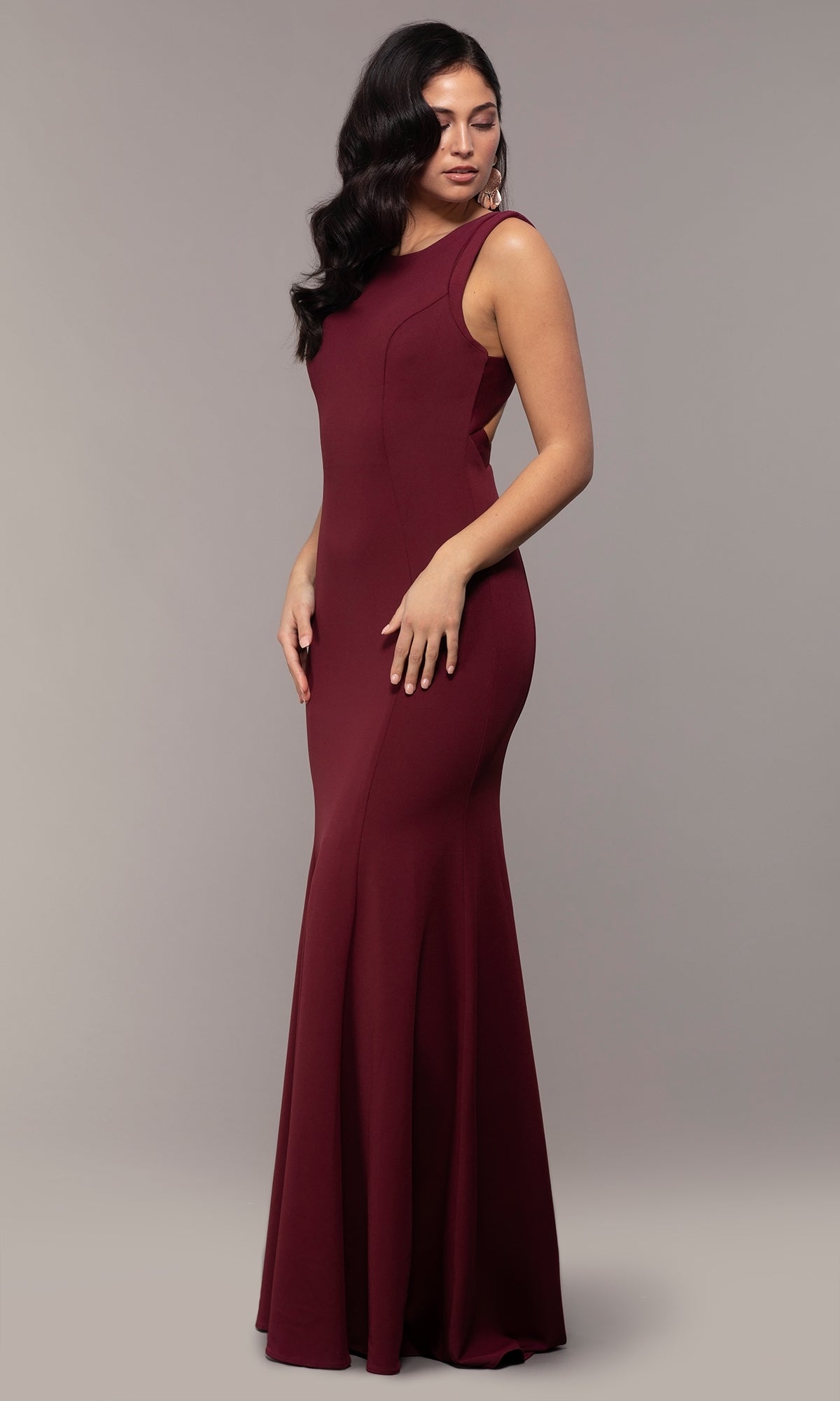 A woman models the Strappy-Open-Back Long Formal Prom Dress 8232, a sleeveless, floor-length burgundy gown with a fitted bodice and flared skirt, posing against a plain gray background.