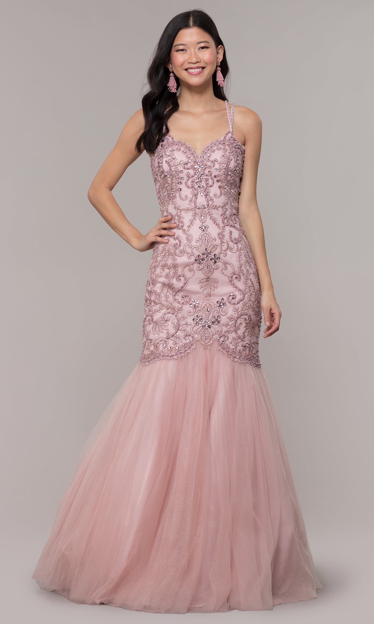 A woman in the Embroidered Tight Sweetheart Mermaid Prom Dress 8352, featuring light pink lace details and a tulle skirt, stands against a plain background, smiling at the camera.