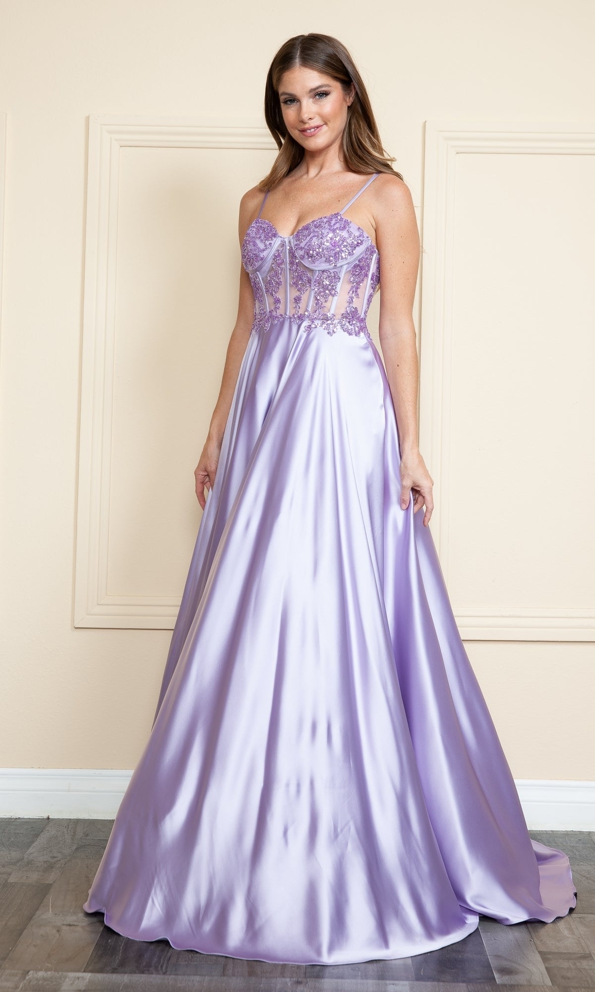 A woman wears the Sheer-Corset Long Satin Prom Dress (Poly USA 9126), featuring lavender satin, an embroidered corset bodice, and a full, floor-length a-line skirt.