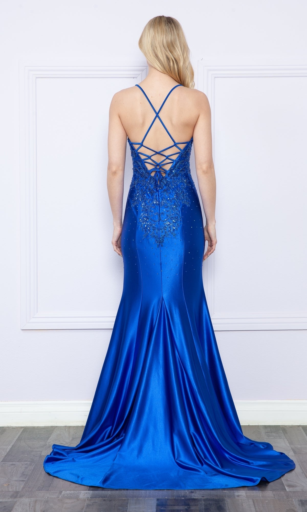 Woman in the Embroidered-Lace-Bodice Long Jersey Prom Dress 9142 stands against a white wall, showcasing its fitted floor-length silhouette—an elegant formal gown under $250, perfect for any special occasion.