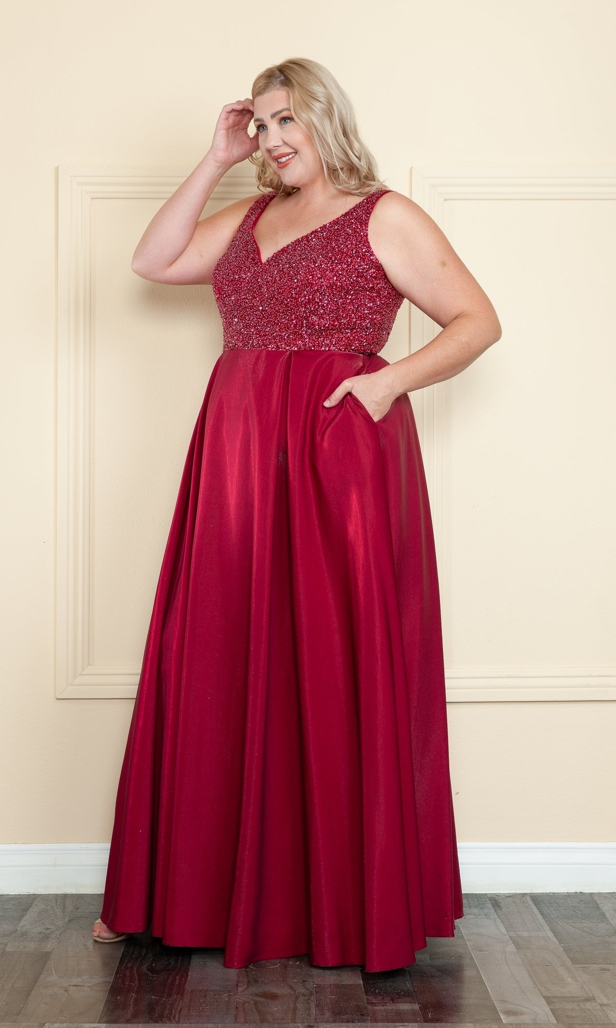A woman smiles while touching her hair in the Beaded-Bodice Plus-Size Long Prom Dress W1066, a sleeveless, floor-length gown ideal for prom or any formal occasion.
