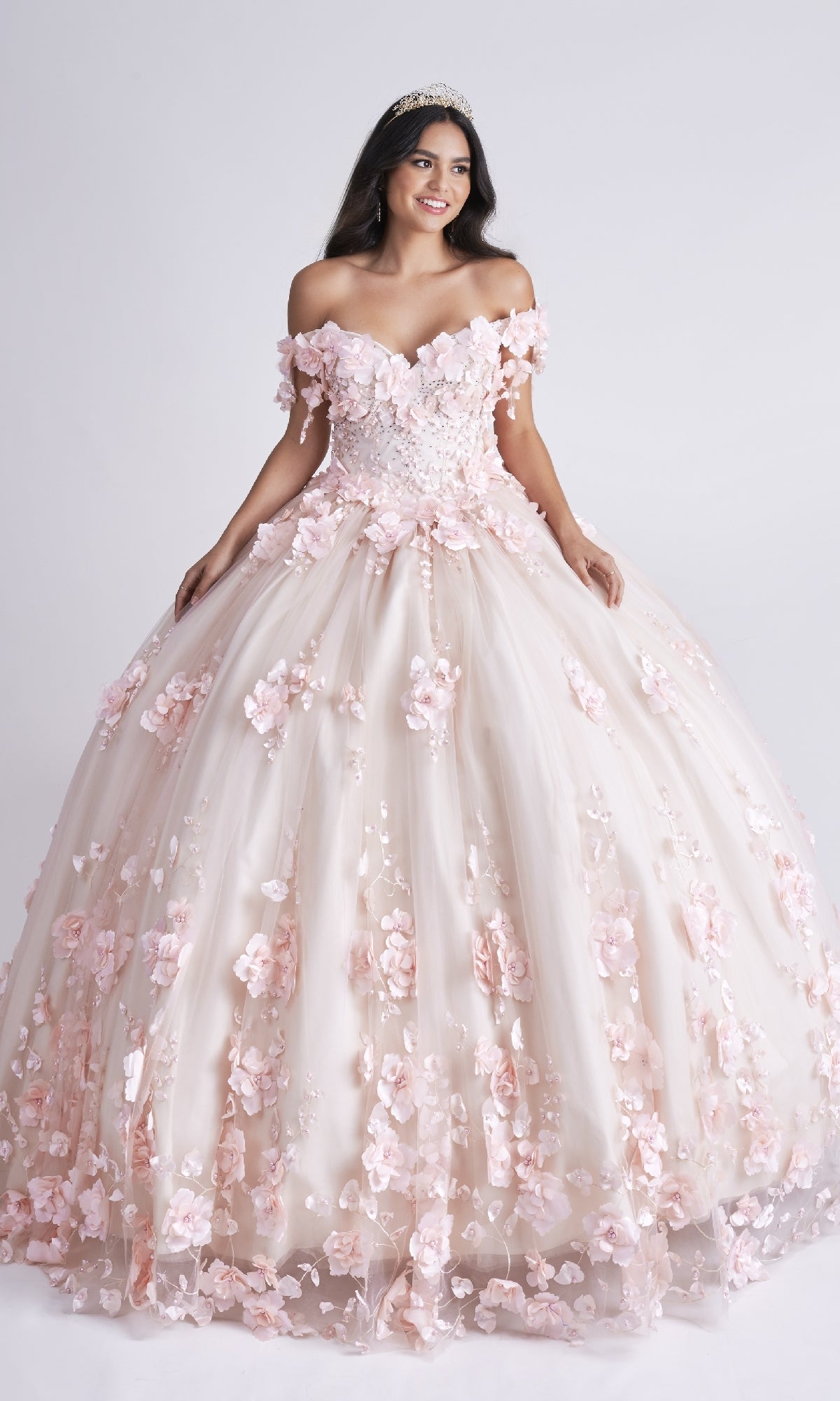 Young woman in the Nina Canacci Q102 long Quinceañera dress with 3D floral appliques and a tiara, standing against a plain white background.