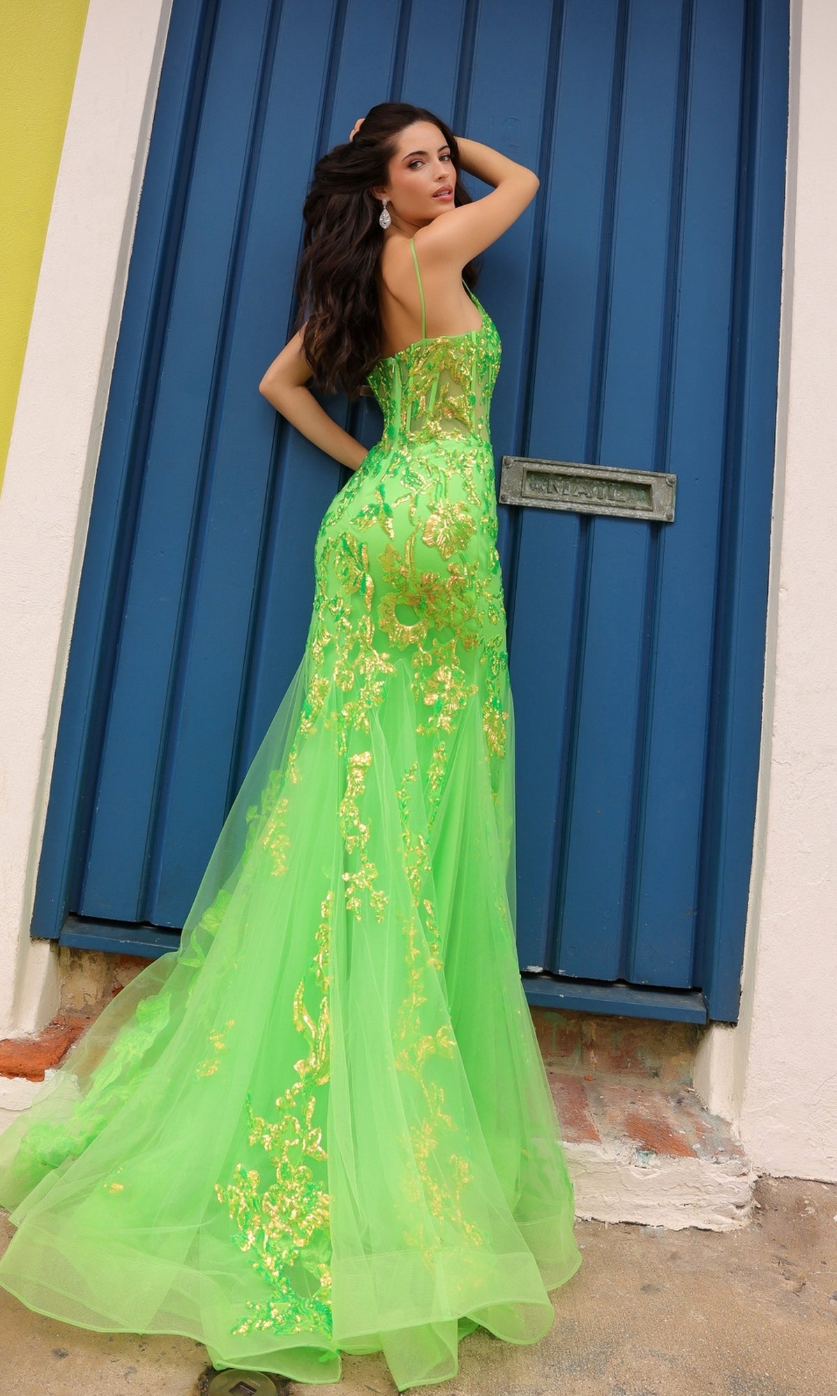 A woman in the Sequin-Lace Long Neon Mermaid Prom Dress Q1390 stands before a blue door, looking over her shoulder.
