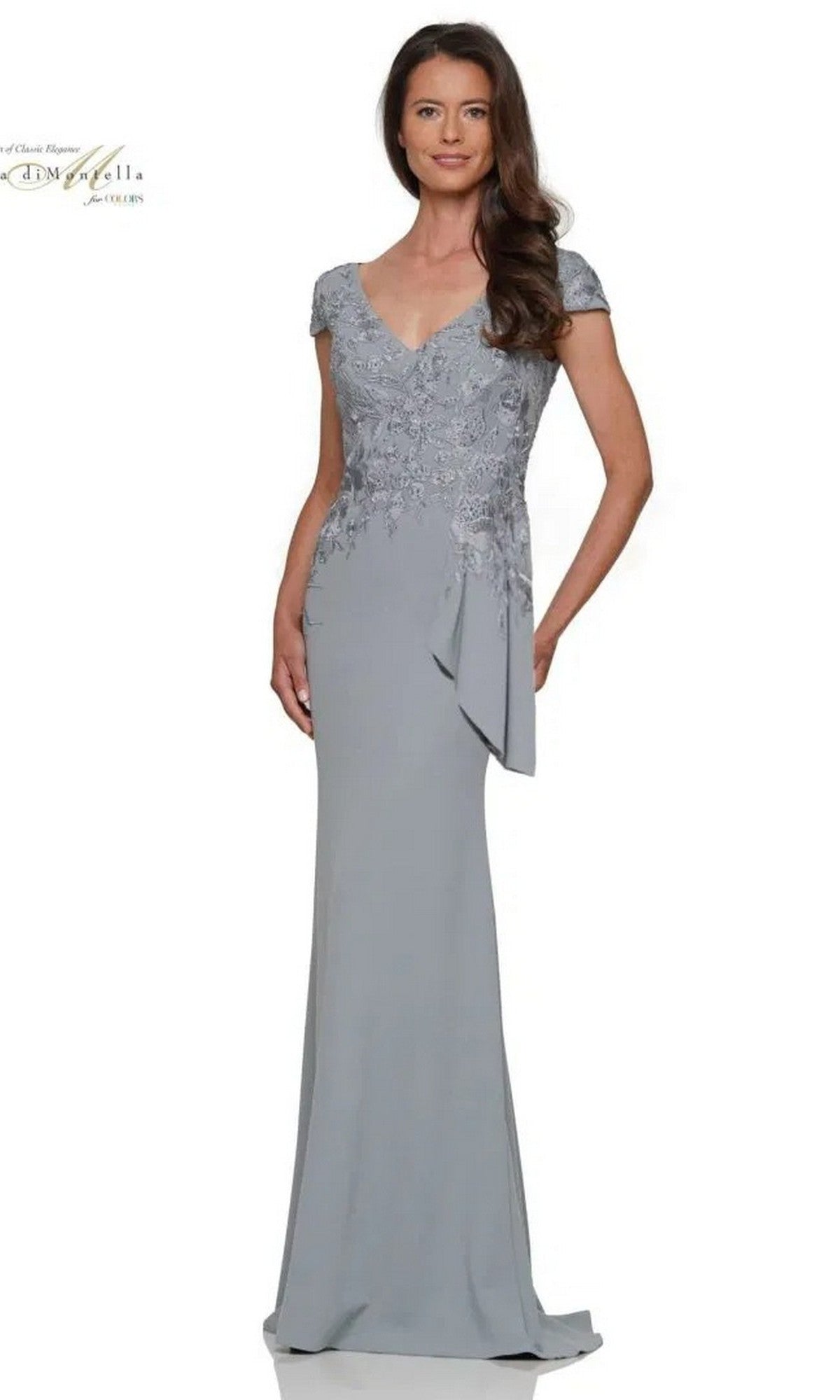 A woman stands against a white background wearing the Rina Di Montella RD2960, a floor-length seaglass formal dress featuring short sleeves and an embroidered bodice.
