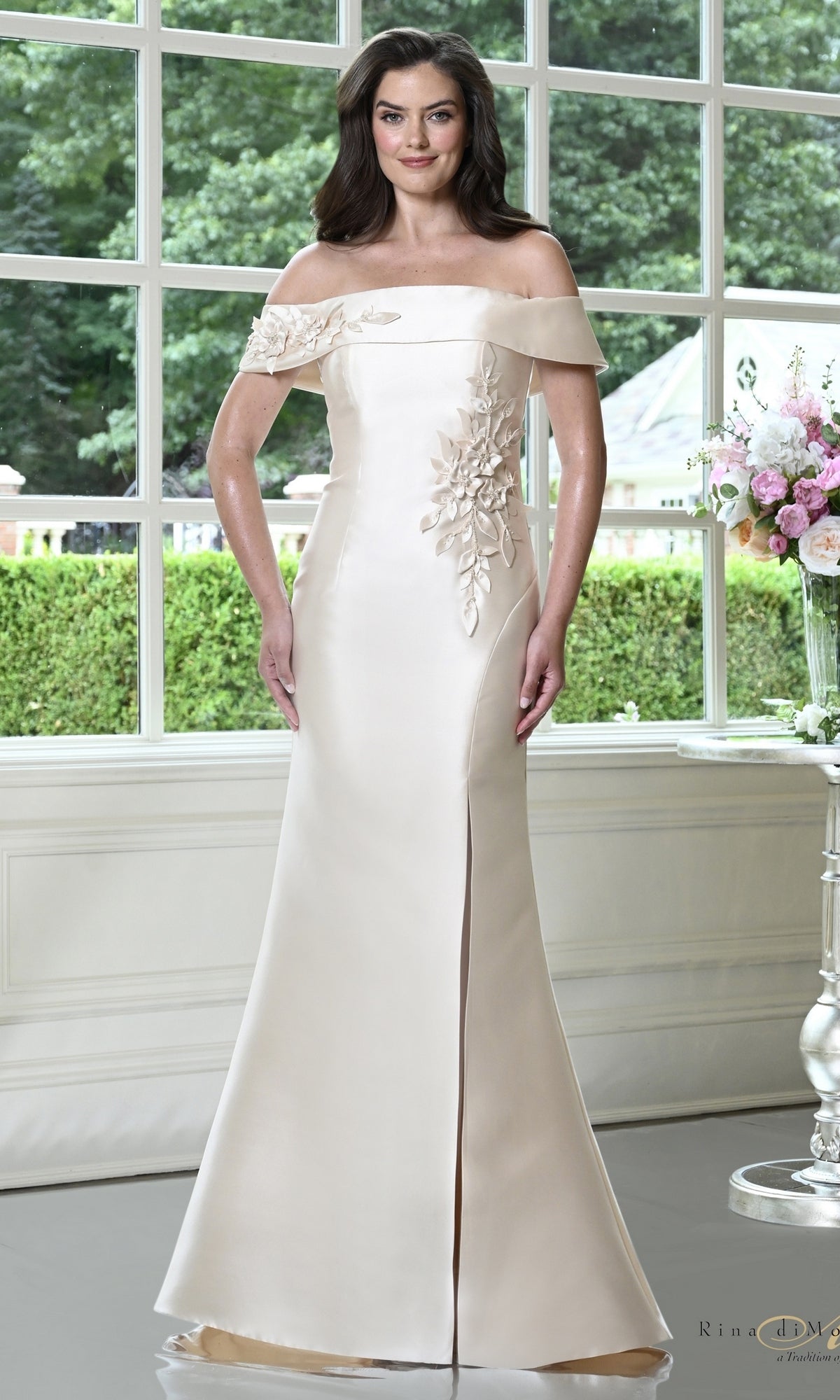 Champagne Rina Di Montella RD3612 folded off-the-shoulder mermaid formal dress featuring floral appliqué and a side slit.