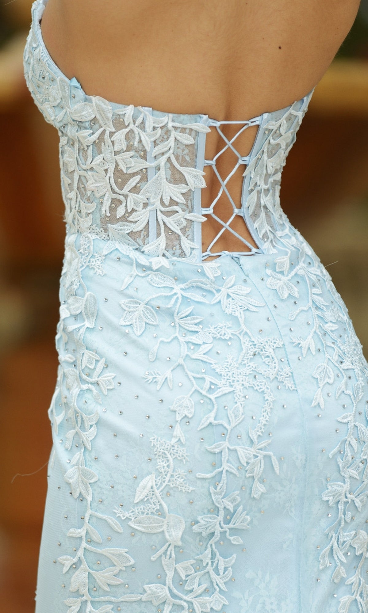 Close-up of the Velvi Long Strapless Lace Mermaid Prom Dress Reva in blue, featuring white floral embroidery, a sheer corset-style back, and crisscross lacing detail.