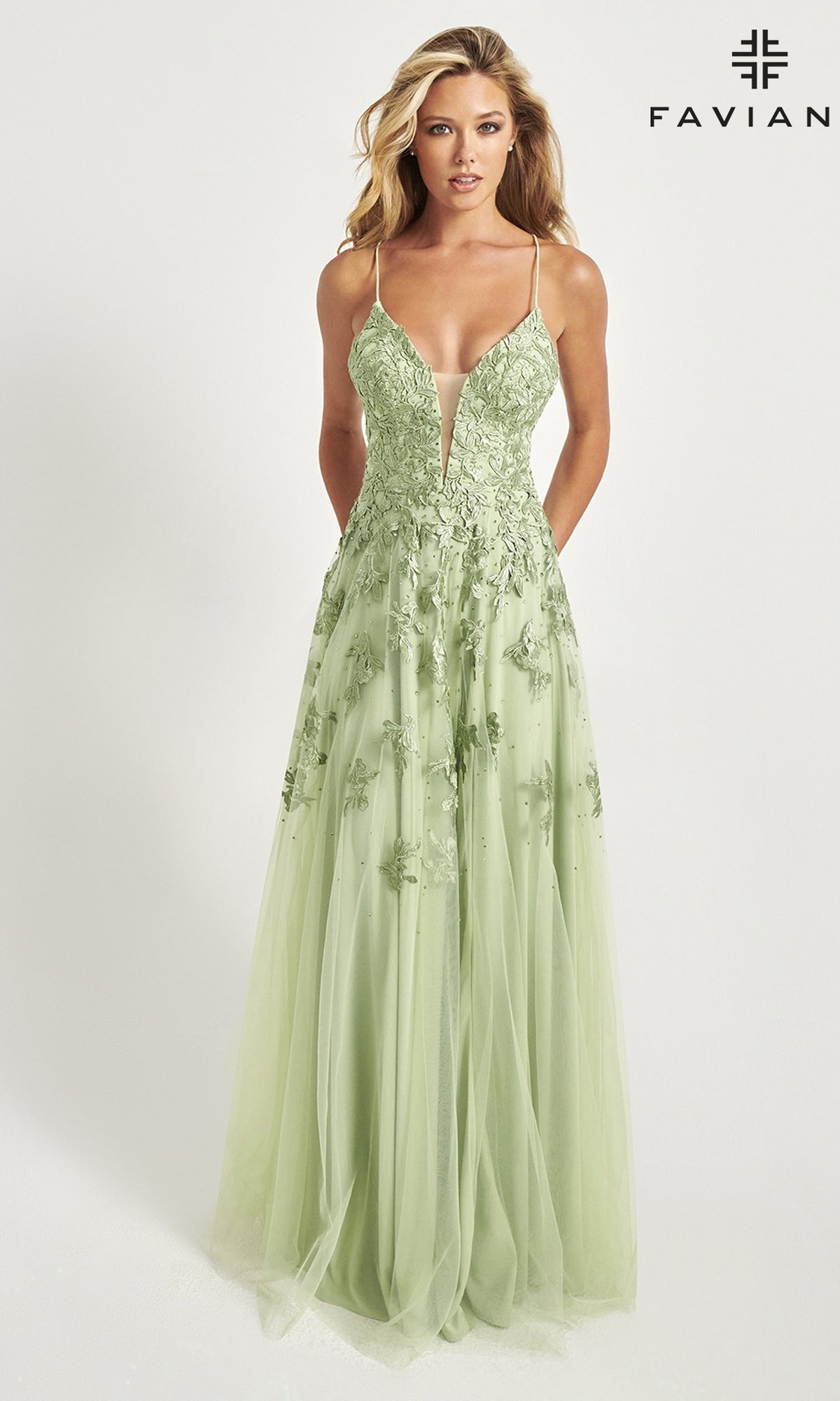A woman wears the Faviana Embroidered A-Line Long Prom Dress in light green, featuring thin straps and delicate 3D floral embroidery, as she stands against a plain white background.