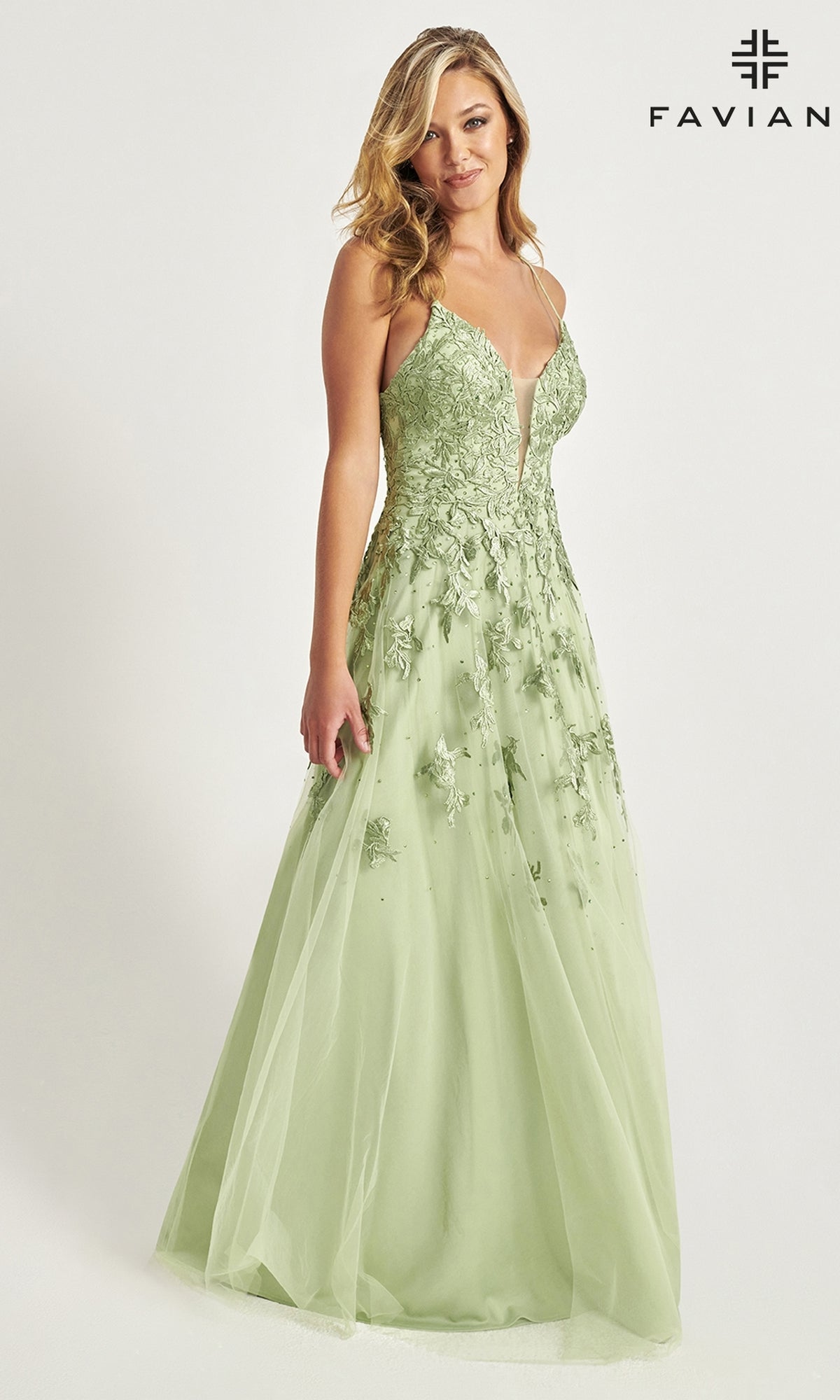 A woman models the Faviana Embroidered A-Line Long Prom Dress in light green, featuring thin straps and 3-D floral embroidery, standing before a plain white backdrop with the Faviana logo at the top right.
