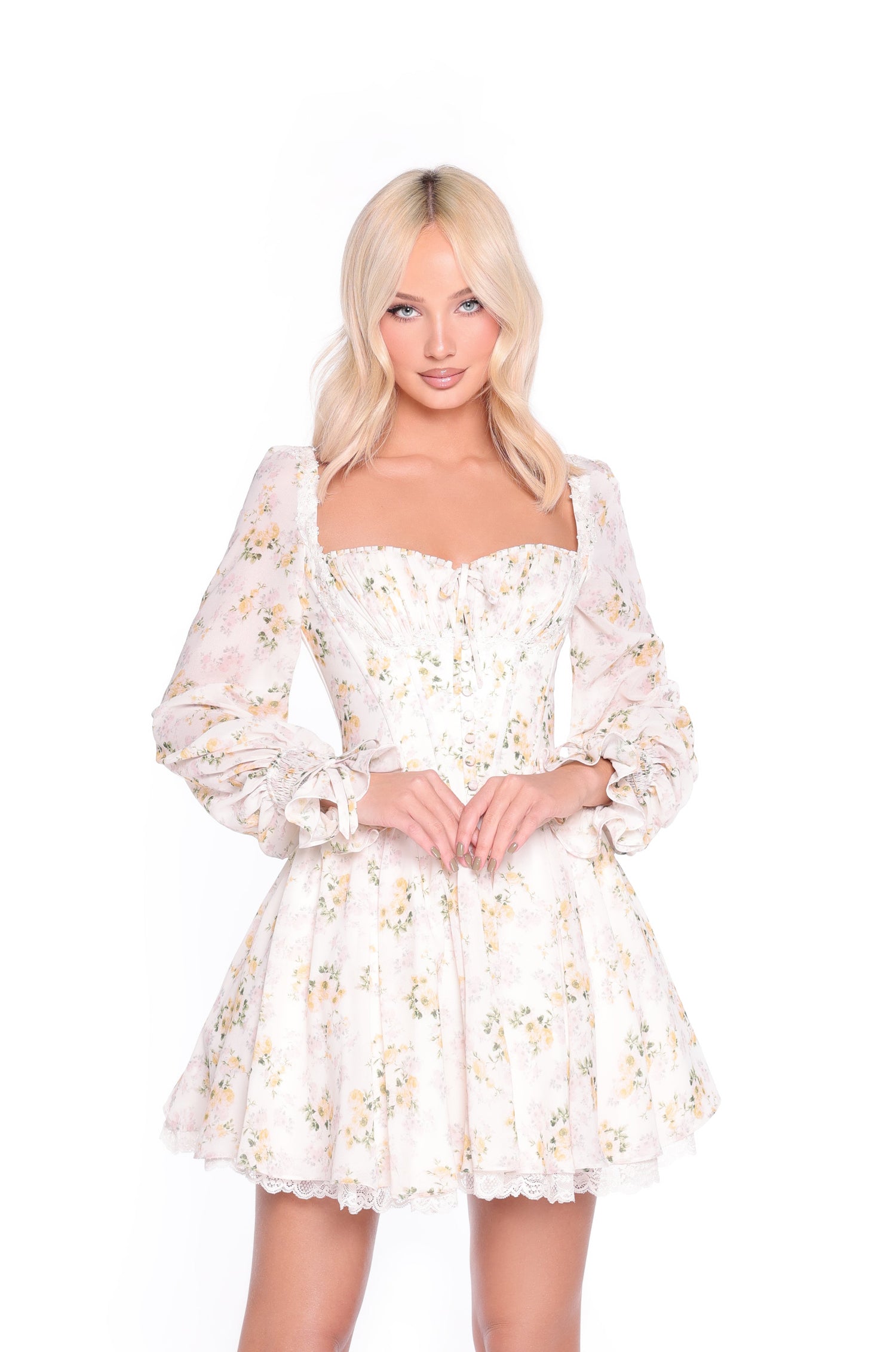 A woman with long blonde hair wears the Sadie Yellow Floral Short Casual Dress, featuring puffed long sleeves and a fitted corset bodice, standing against a plain white background.