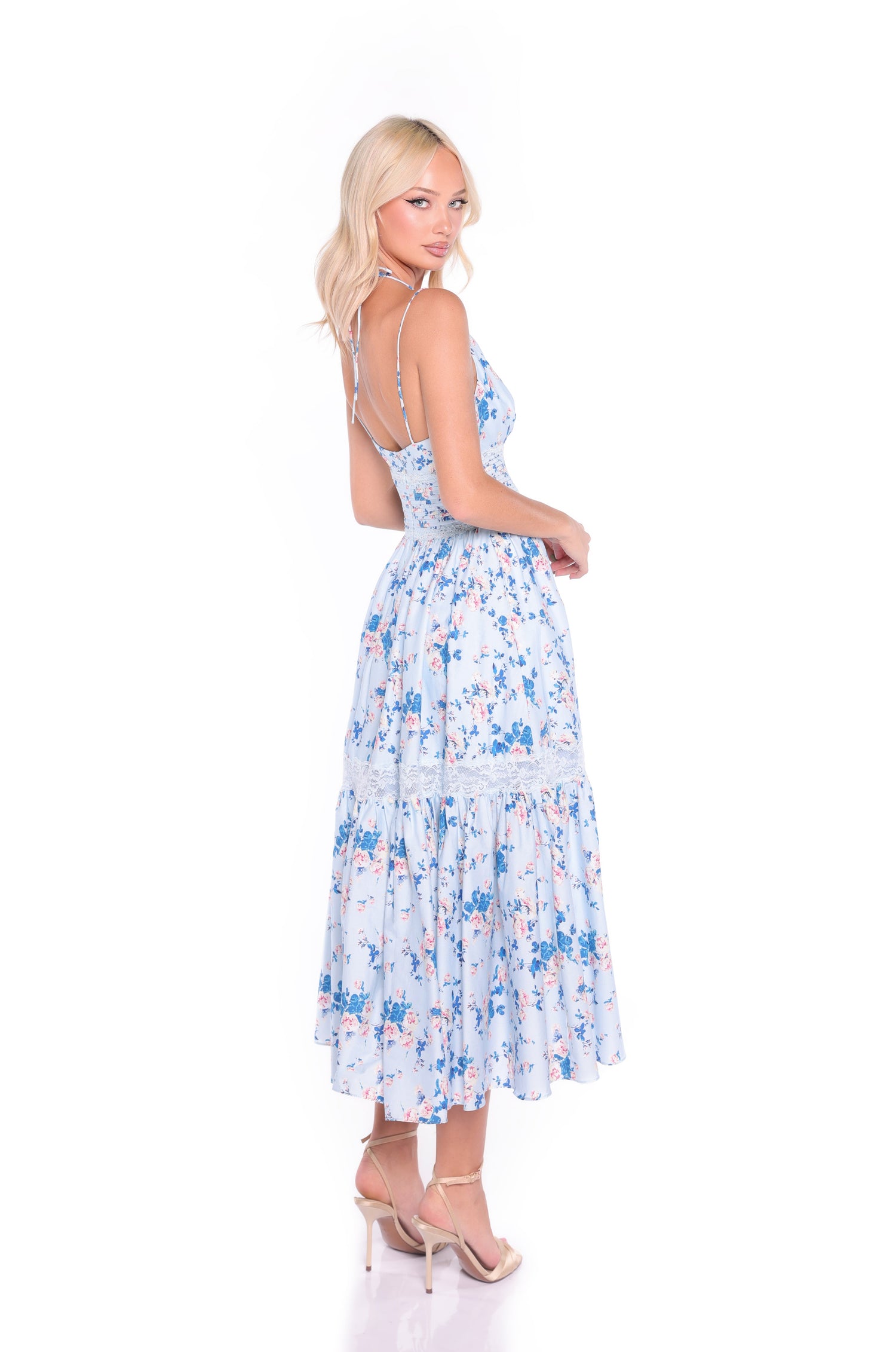 A woman wears the Solene Blue Floral Midi Casual Dress, featuring a v-neck and spaghetti straps, posing in beige high heels against a white background.