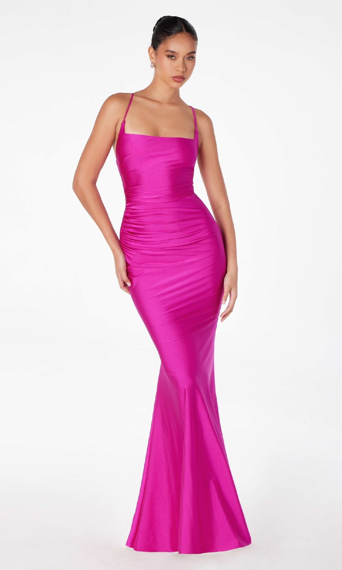A woman models the Strappy Open-Back Long Prom Dress: Astee T3001, a form-fitting, bright pink gown with straps and an open back, standing against a plain white background.