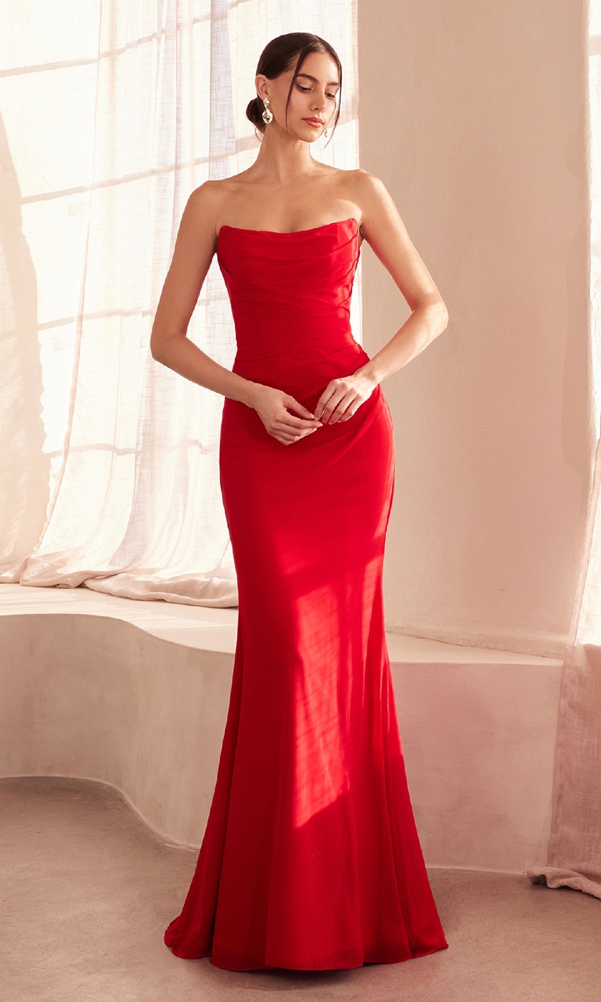 A woman stands indoors wearing the Lace-Up Strapless Prom Gown: Amoris T702 with her hair tied back, hands together at her waist, highlighting the gown's elegant design.