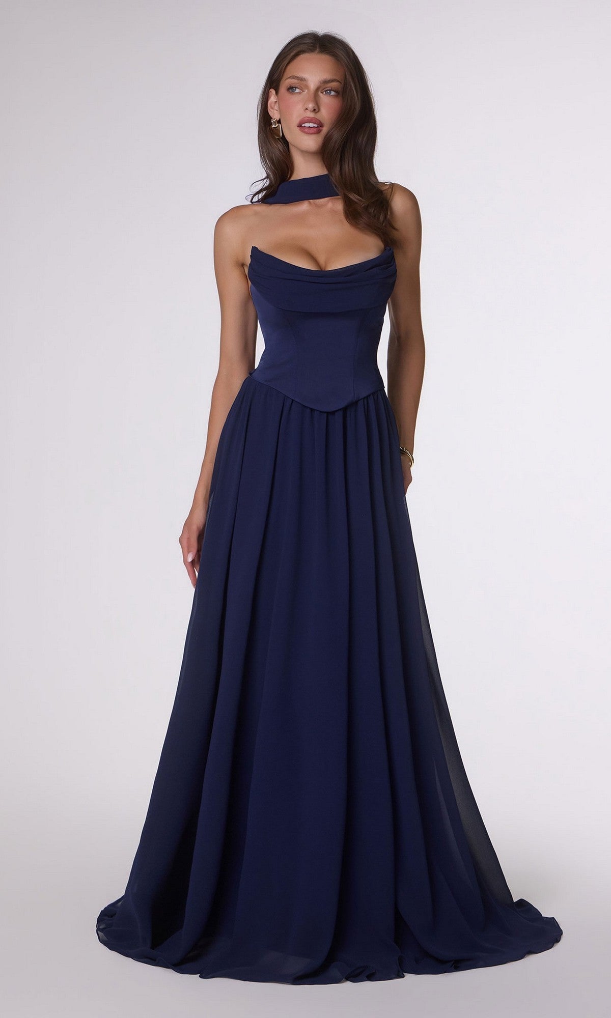 A woman stands against a plain background wearing the Amoris T741 long prom dress, featuring a floor-length navy blue design with a strapless satin corset bodice and a matching neck scarf.