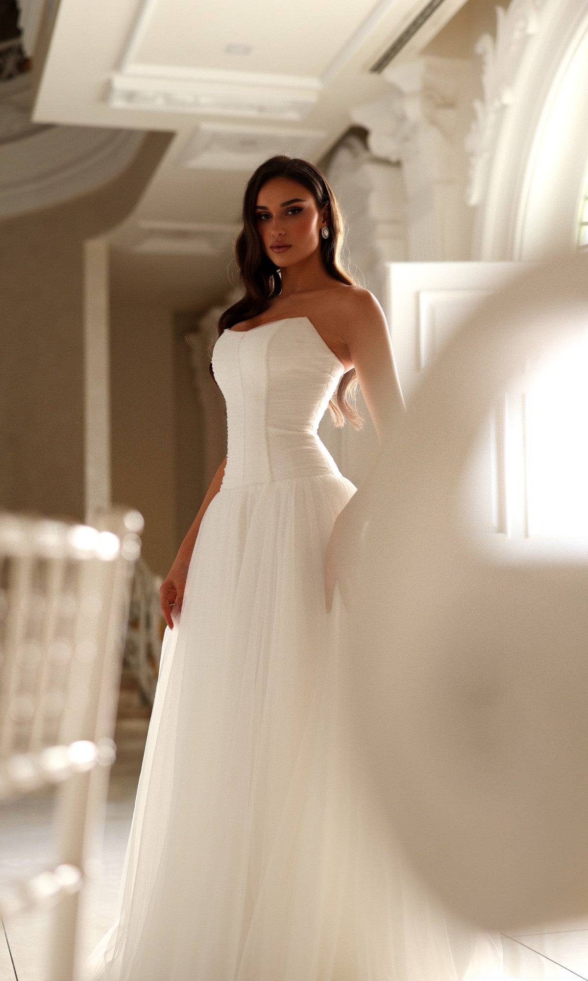 Woman wearing a Tina Holly TE710 long wedding dress featuring a strapless corset bodice and a full tulle skirt.