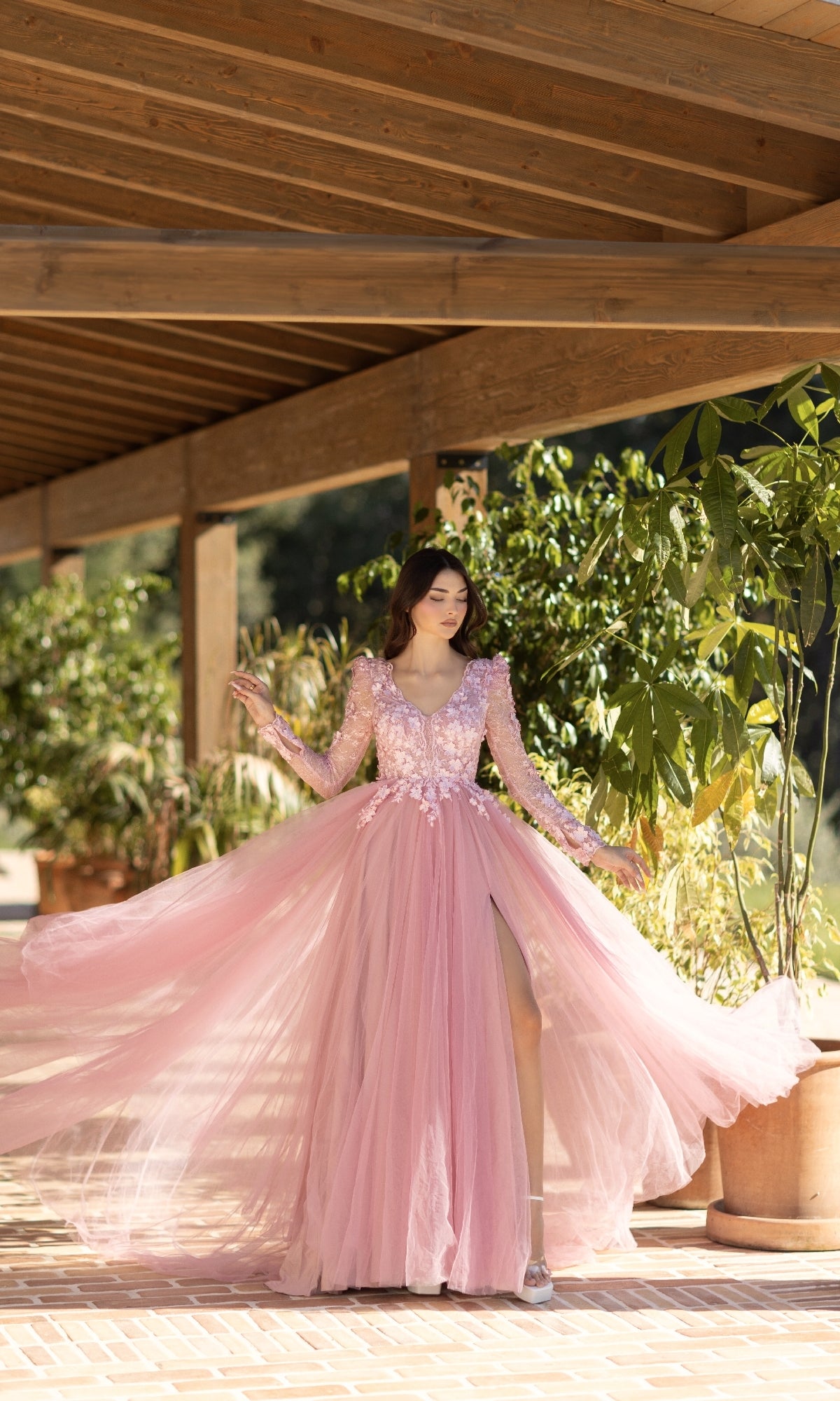A woman in the Long Pink Formal Dress: Tina Holly TF318F, featuring a lace bodice and a-line tulle skirt, stands on a tiled terrace with potted plants and wooden beams in the background.