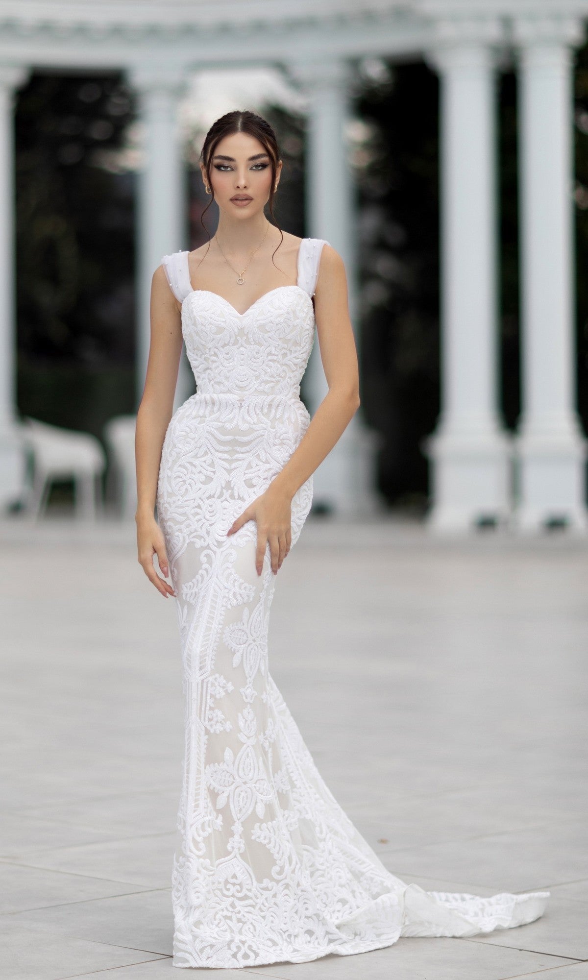 A woman wearing the Off-Shoulder White Bridal Gown: Tina Holly TW103 stands outdoors in front of white columns.