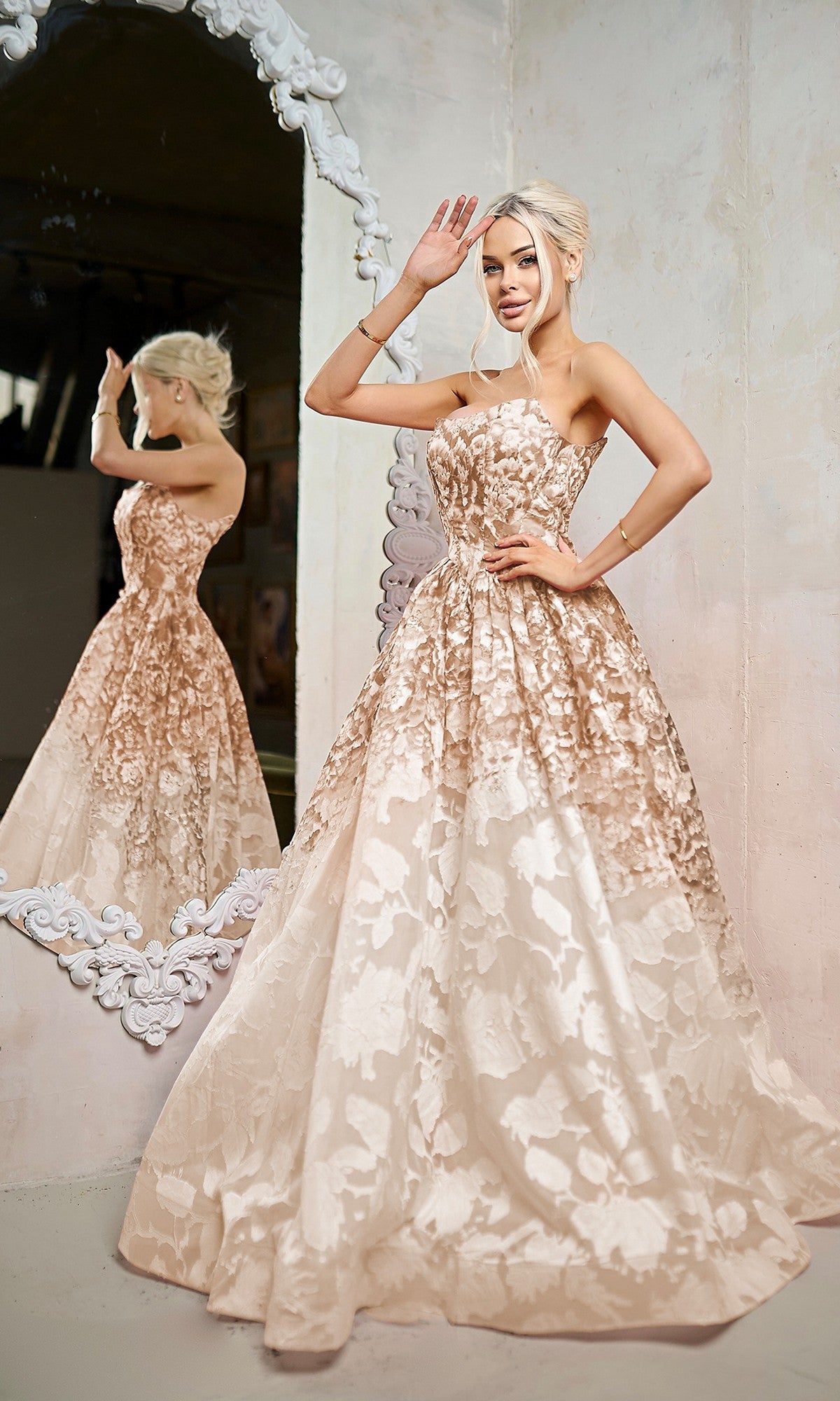 A woman in the Long Formal Dress: Tina Holly TW624, a floor-length floral champagne gown, poses by an ornate mirror with her reflection visible in the background.