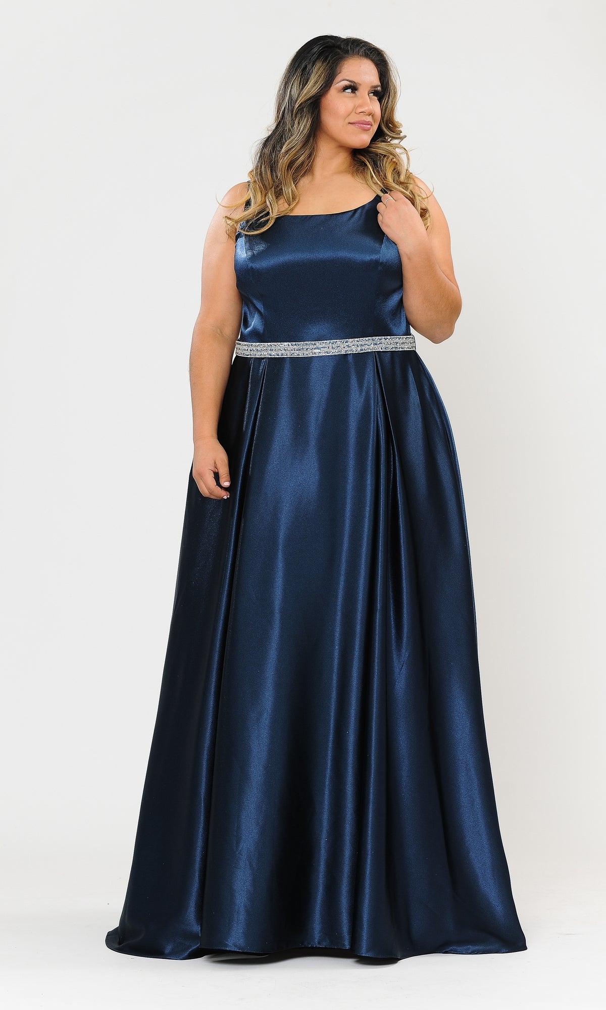 A woman in the Sleeveless Plus-Size Long Belted Prom Dress W1010, a navy floor-length gown, stands against a plain white background.