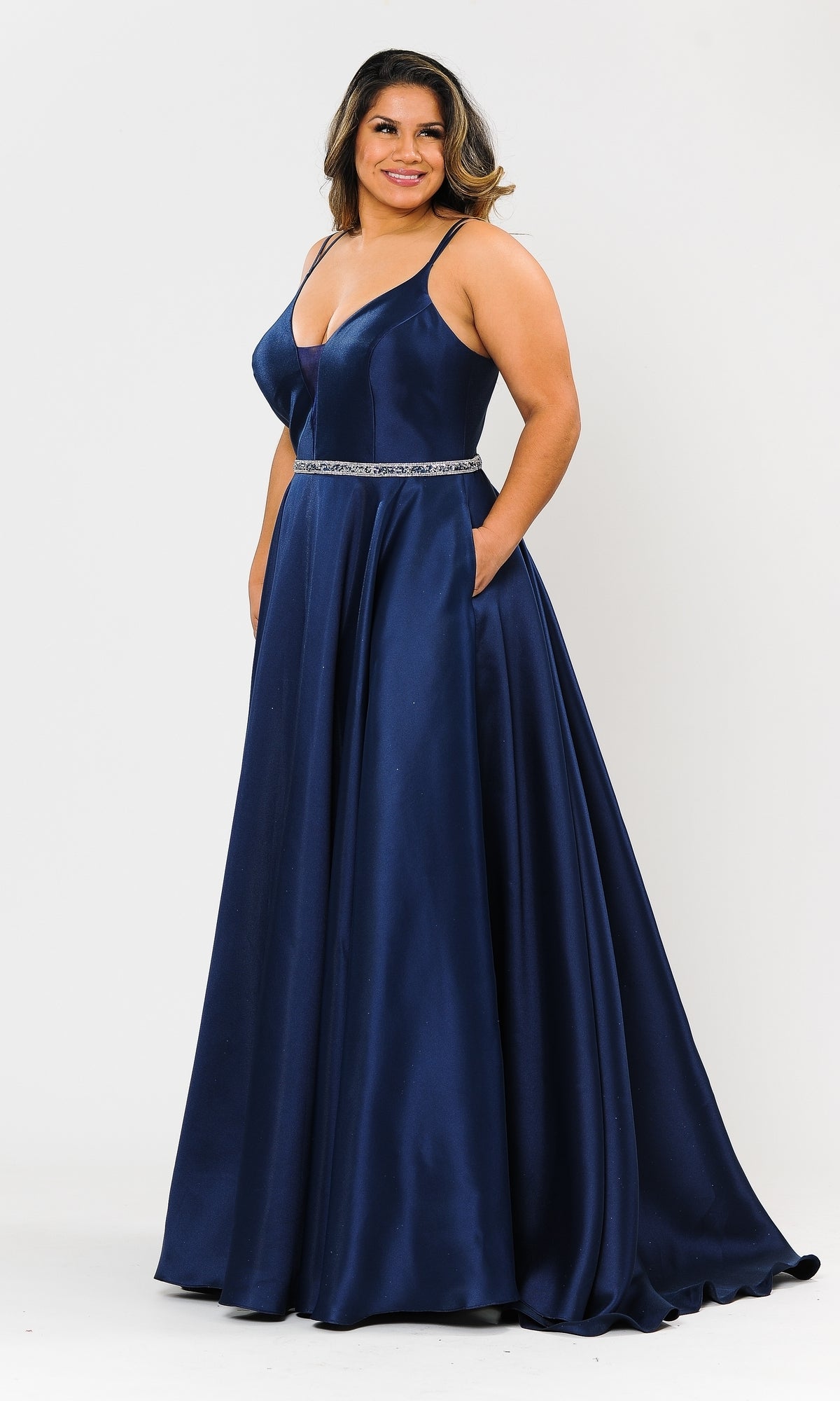 A woman wears the Plus-Size Long Prom Dress with Pockets W1106 in navy, featuring a floor-length satin A-line design, V-neckline, thin straps, jeweled waistband, and convenient pockets.