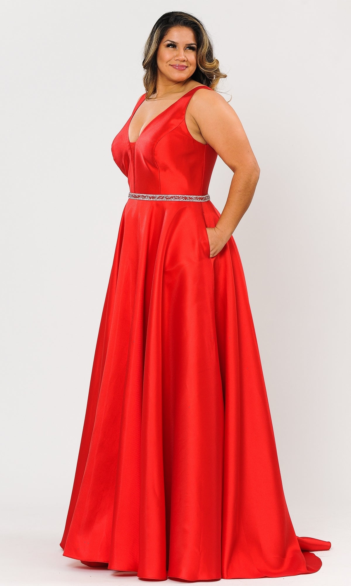 A woman poses against a plain background in the V-Neck Plus-Size Long Prom Dress with Pockets W1108—a sleeveless, floor-length red gown featuring a V-neckline, beaded waistband, and convenient dress pockets for her hands.