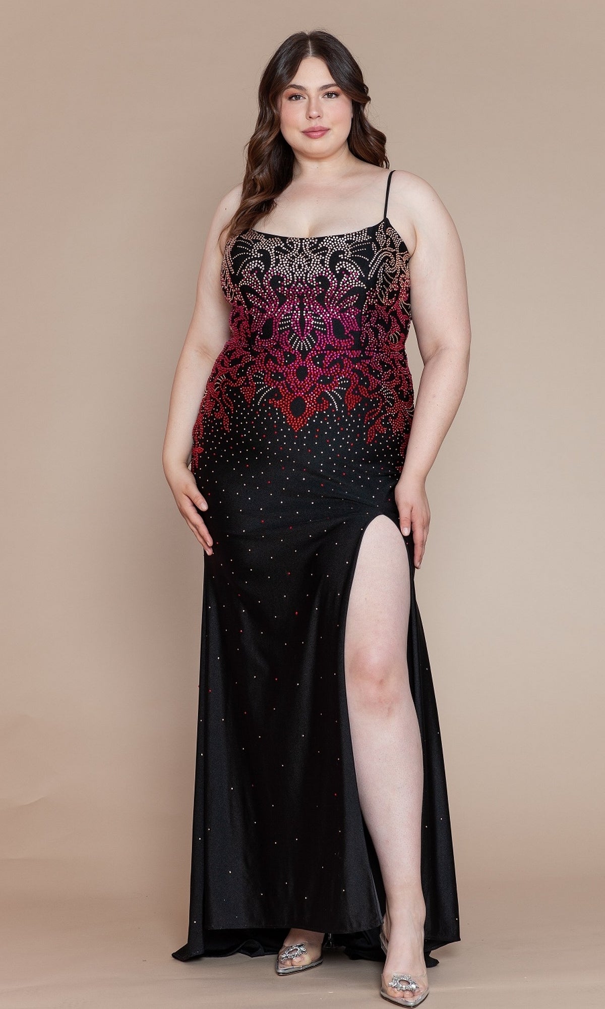A woman wears the Ombre-Beaded Plus-Size Long Prom Dress W1138 in black, featuring sparkling beads, a thigh-high slit, and spaghetti straps, as she stands against a beige background.