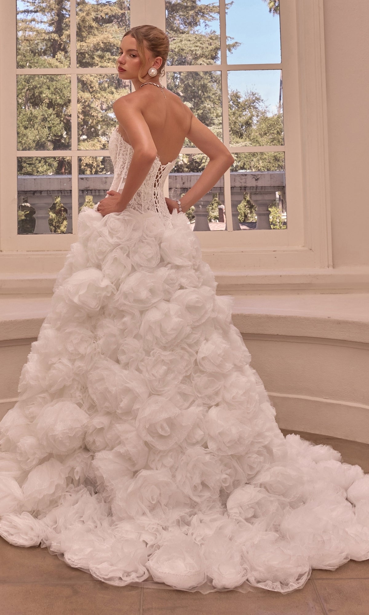 A person wearing the Strapless Ball Gown Wedding Dress: Andrea & Leo WL092, featuring a corset bodice and a skirt covered in layered fabric rosettes.