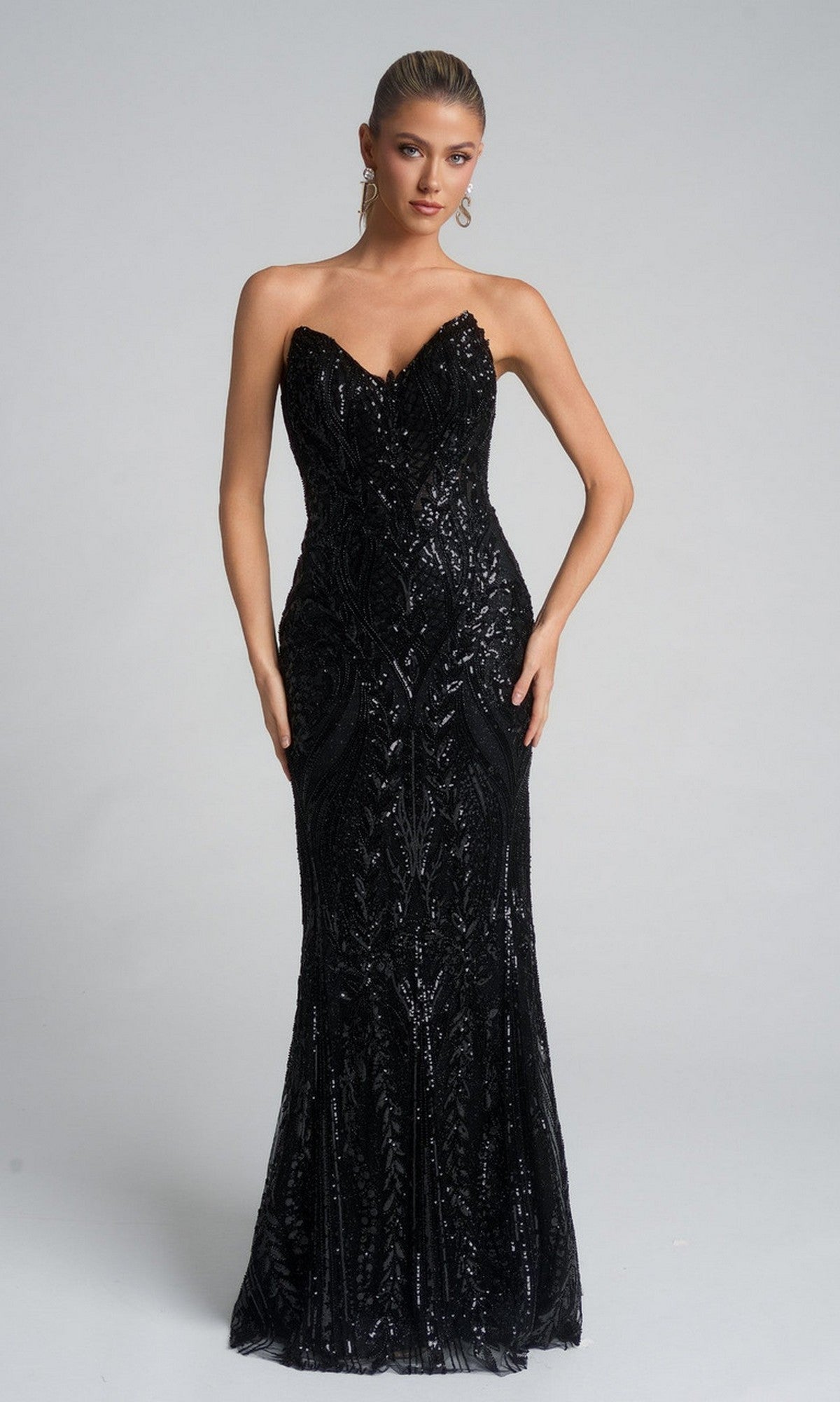 A woman models the Portia and Scarlett XO134 long formal dress in black, featuring a strapless sweetheart neckline, sparkling sequins, and a floor-length fitted silhouette against a plain background.