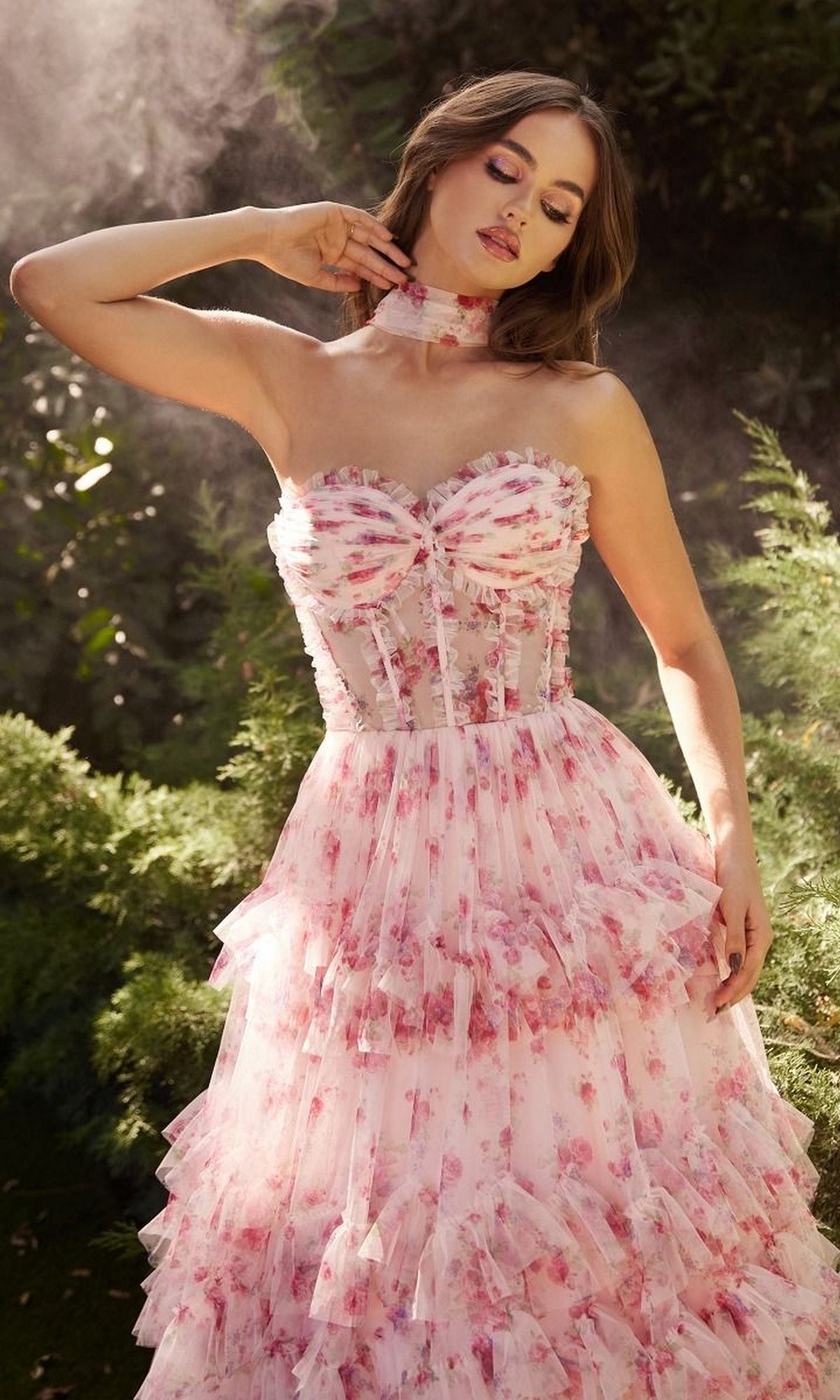 A woman stands outdoors in a garden wearing the Andrea and Leo A1334 Strapless Print Prom Dress with ruffles and a matching choker.