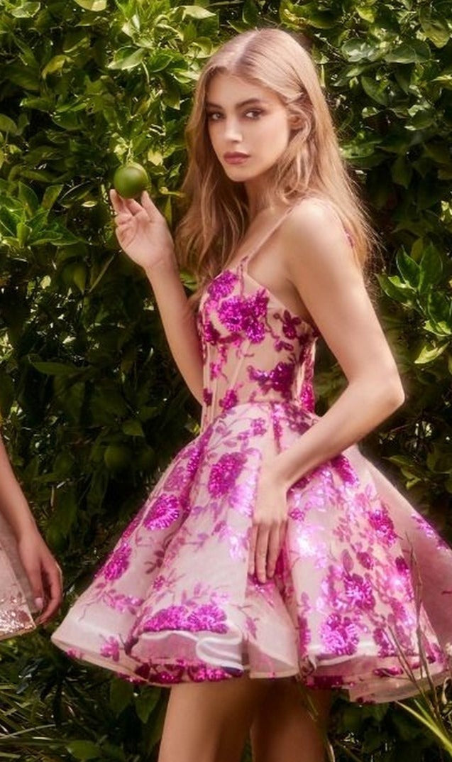 A woman in the Short Sequin-Print Babydoll Hoco Dress A1347 stands outdoors, holding a green fruit amid lush greenery.