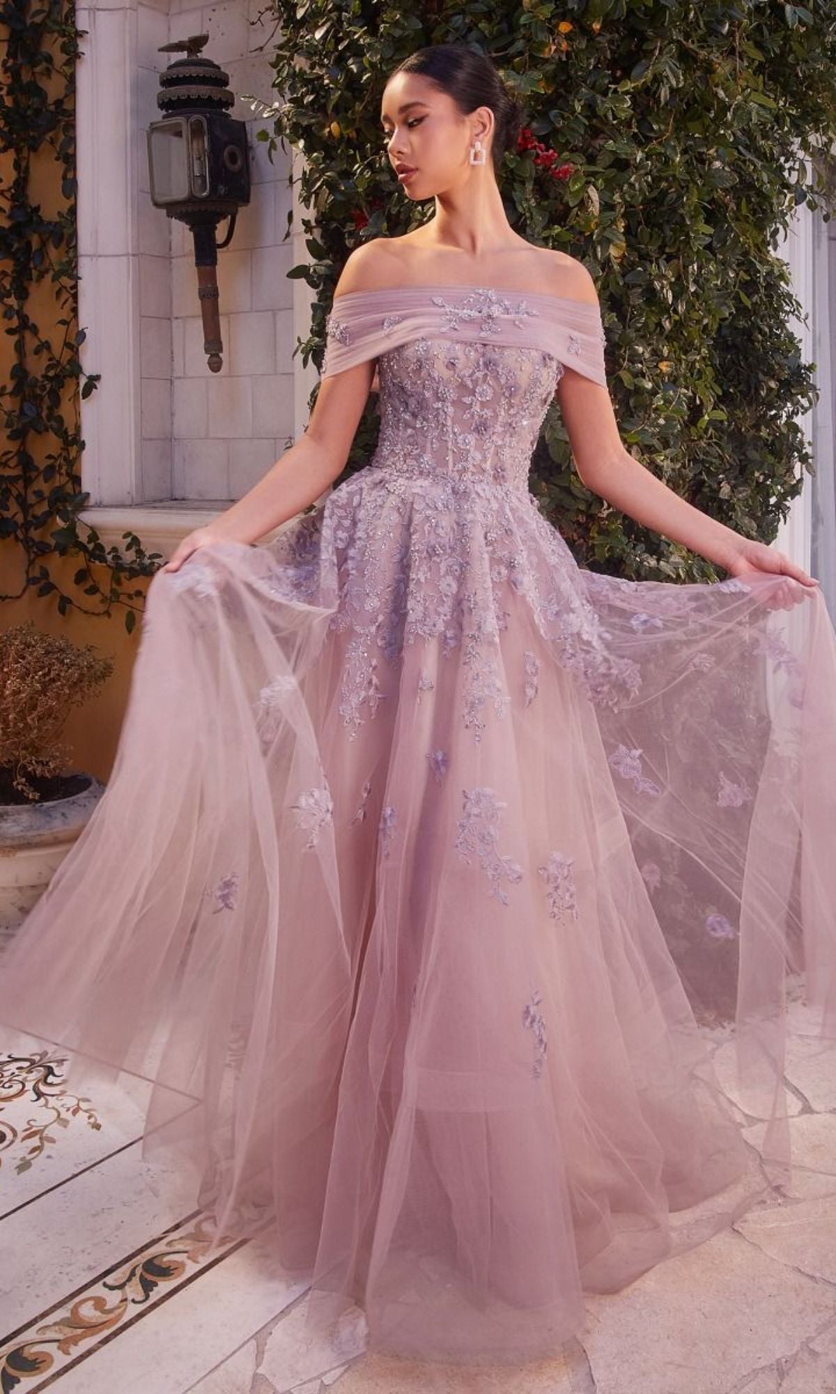 A woman stands outdoors wearing the Long Strapless Sweetheart A-Line Prom Dress A1348 in lavender, featuring floral embroidery and sheer tulle fabric, gracefully holding the skirt out on both sides.