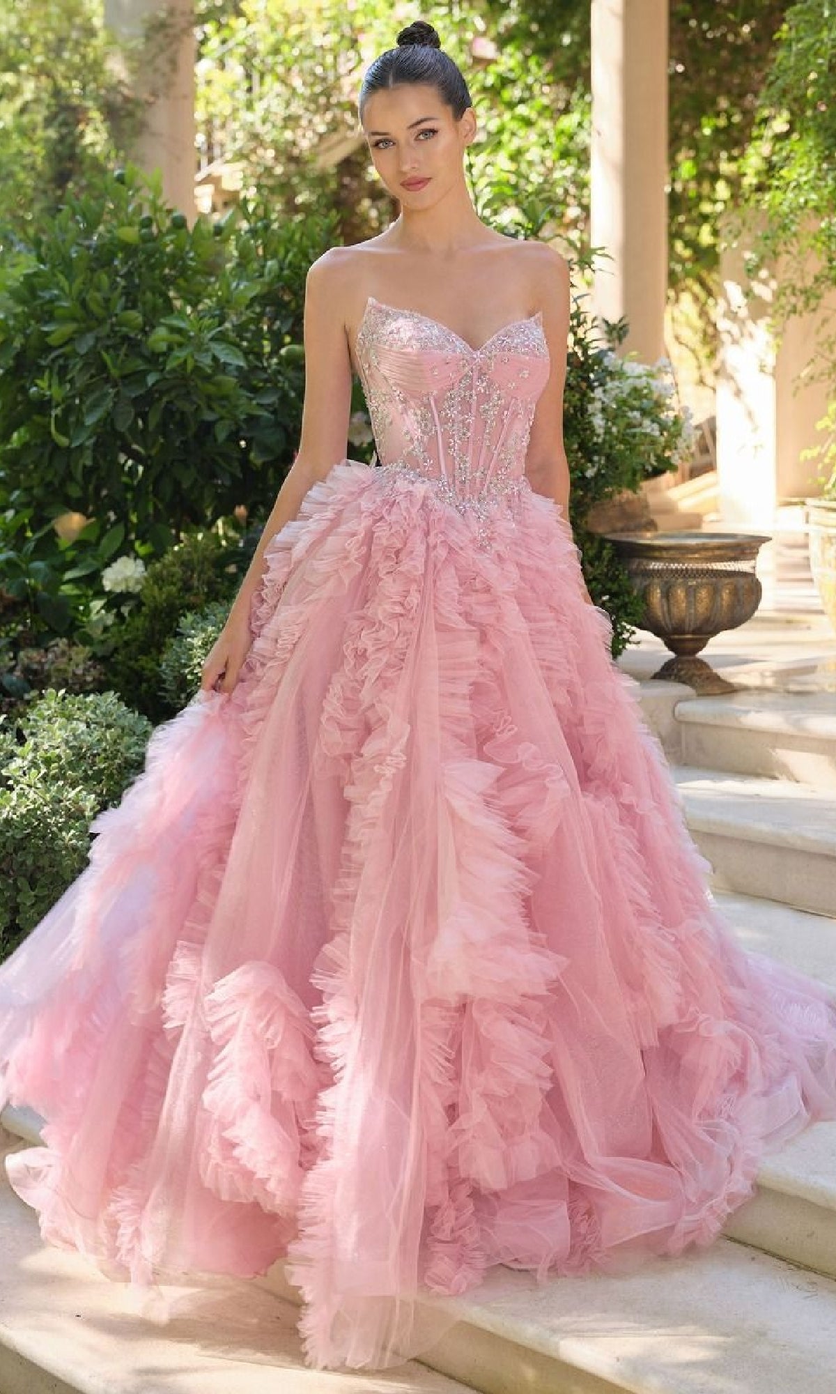 Pink ball gown with intricate details worn by a woman outdoors.