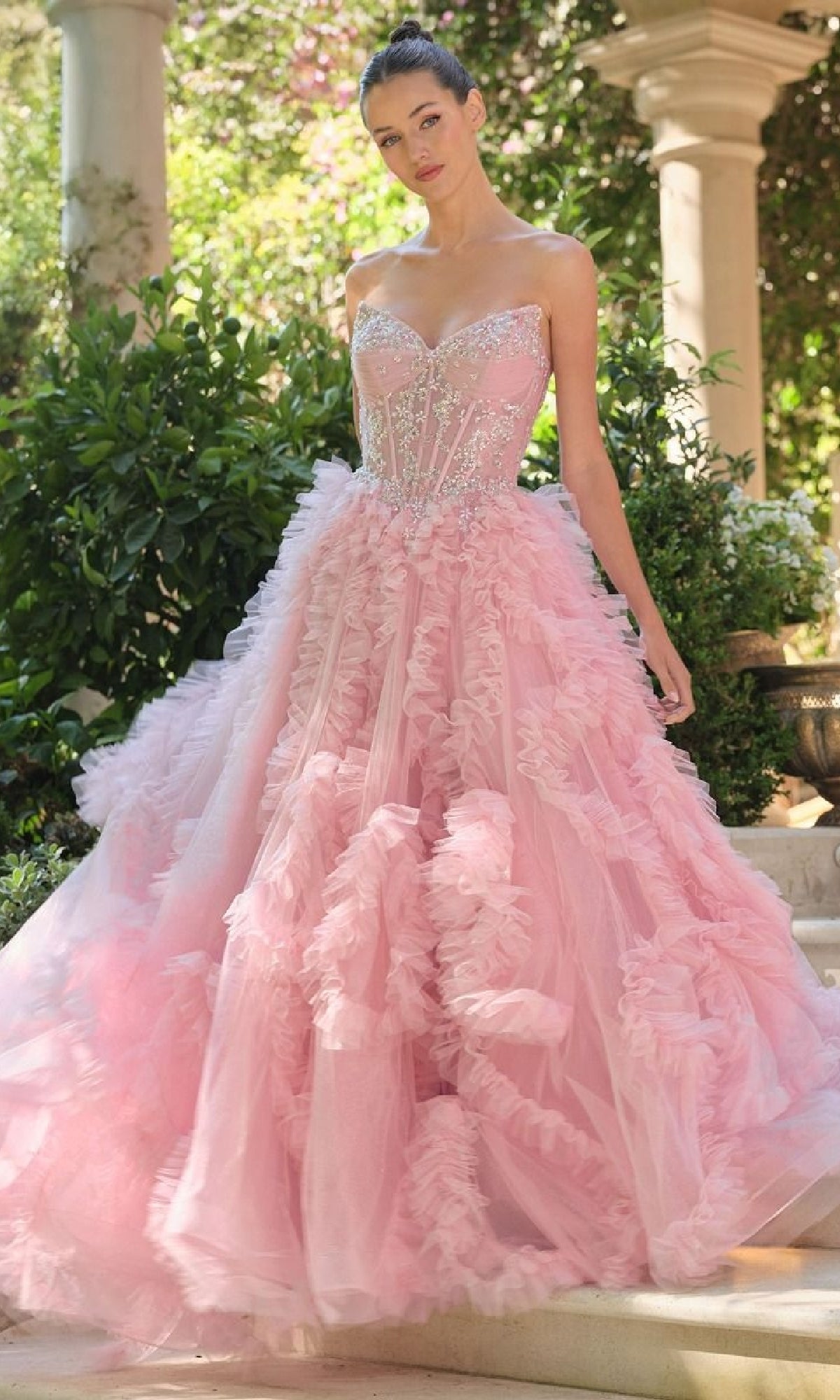 Pink ball gown with intricate details worn by a model outdoors.