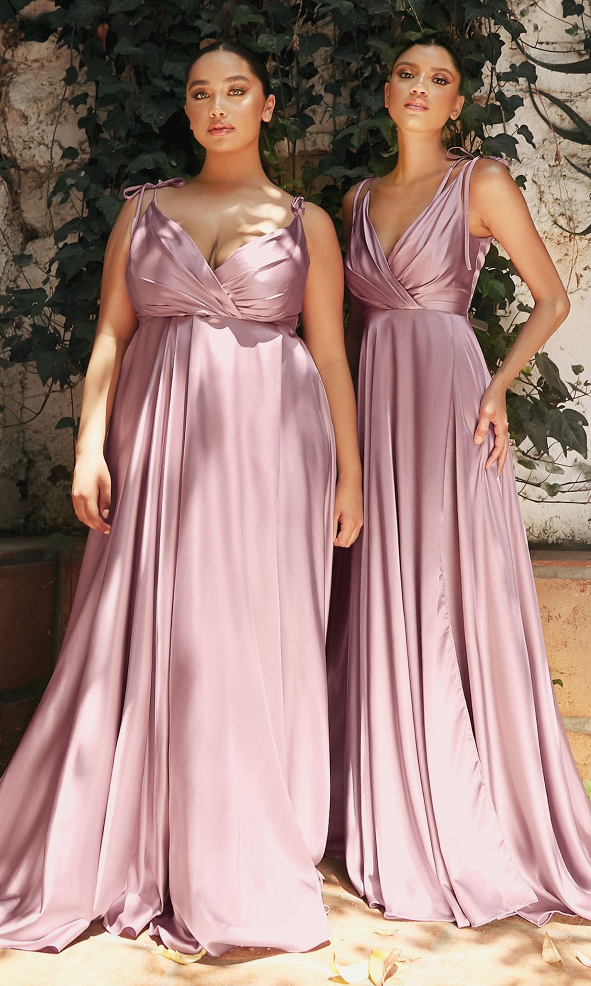 Two women stand outdoors in lush greenery, each wearing the Shoulder-Tie Long Satin V-Neck Prom Dress BD105—a mauve a-line gown with gathered bodice, ideal for those seeking elegant formal dress inspiration.