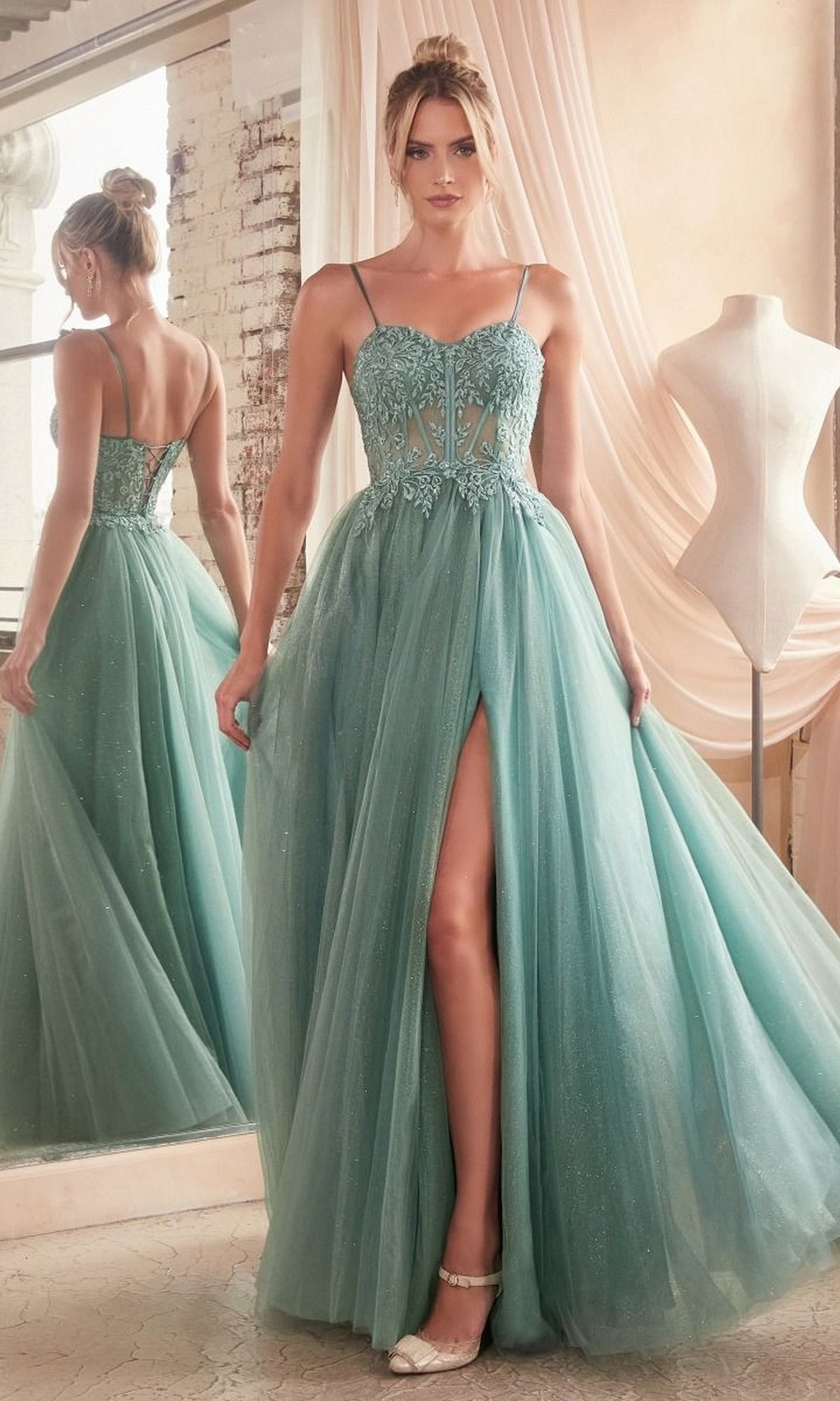 A woman in a mint green Sheer-Waist Long Glitter-Tulle Prom Dress C150 with a thigh-high slit and beaded floral bodice stands by a mirror next to a dress form.