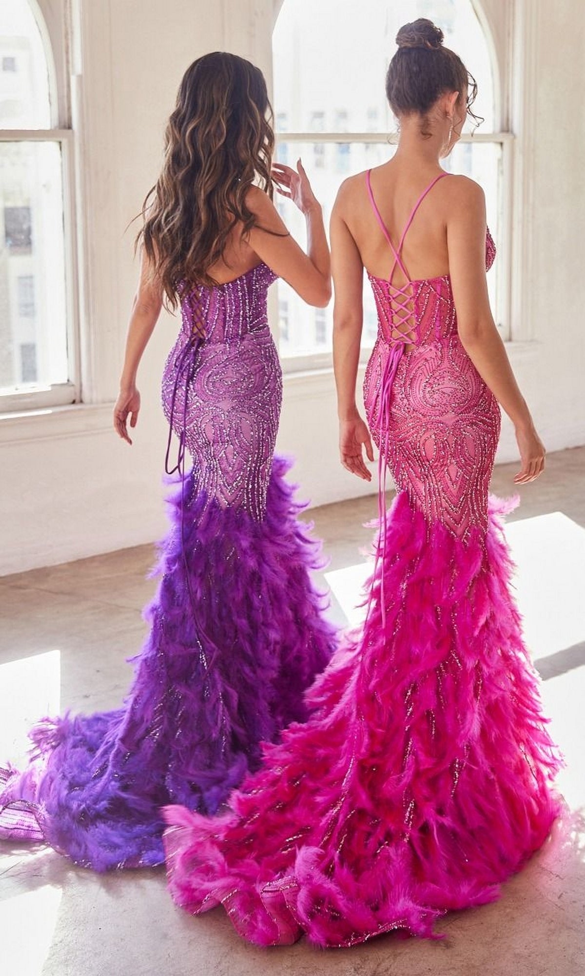 Two women model the Feather-Trim Long Beaded Mermaid Prom Dress CC2308—one in purple, one in pink—standing side by side by bright windows. Their glamorous floor-length gowns are perfect for any special occasion.