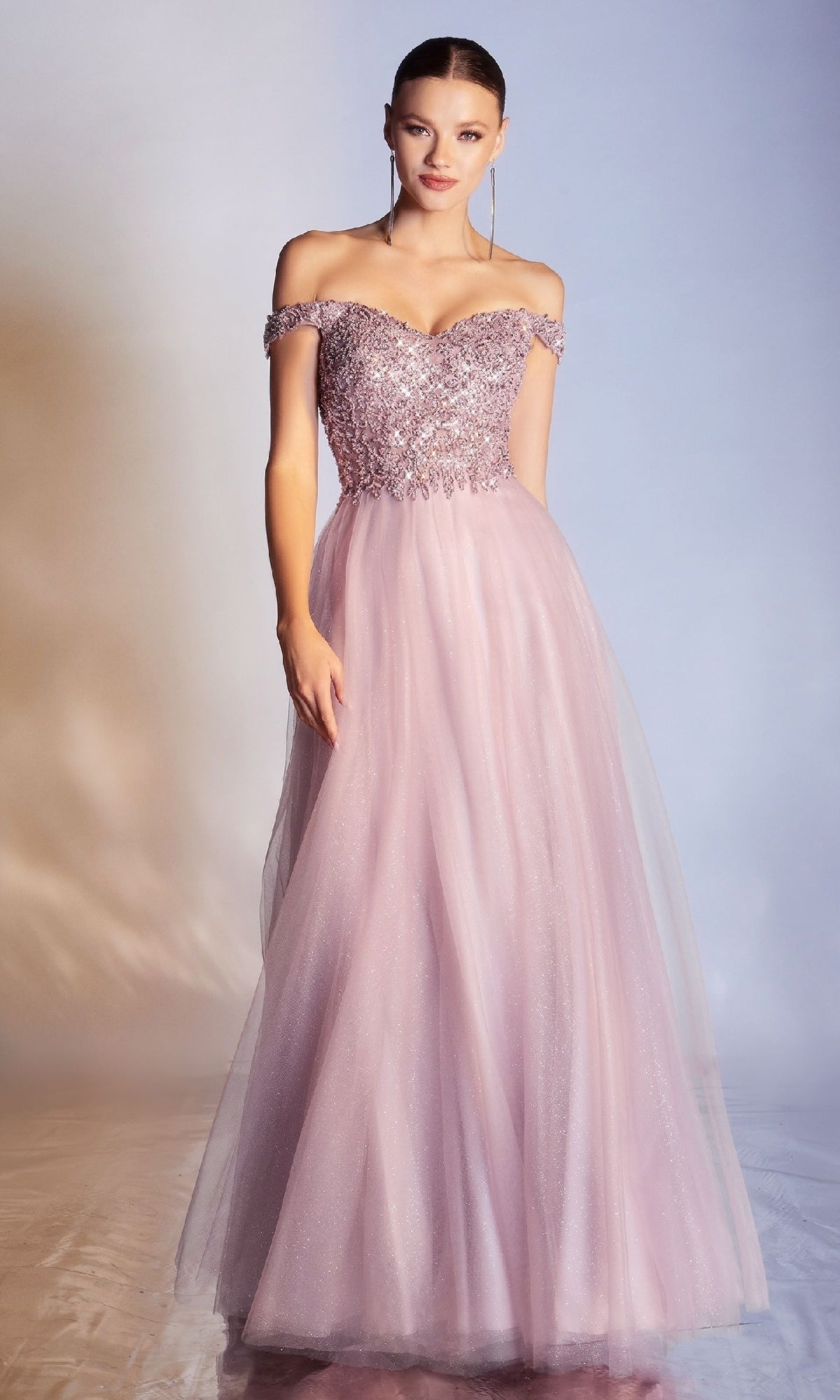 A woman wears the Beaded-Bodice Long Prom Dress: Ladivine CD0177, featuring a light pink, off-the-shoulder design with a sequined bodice and flowing tulle skirt, standing against a neutral background.