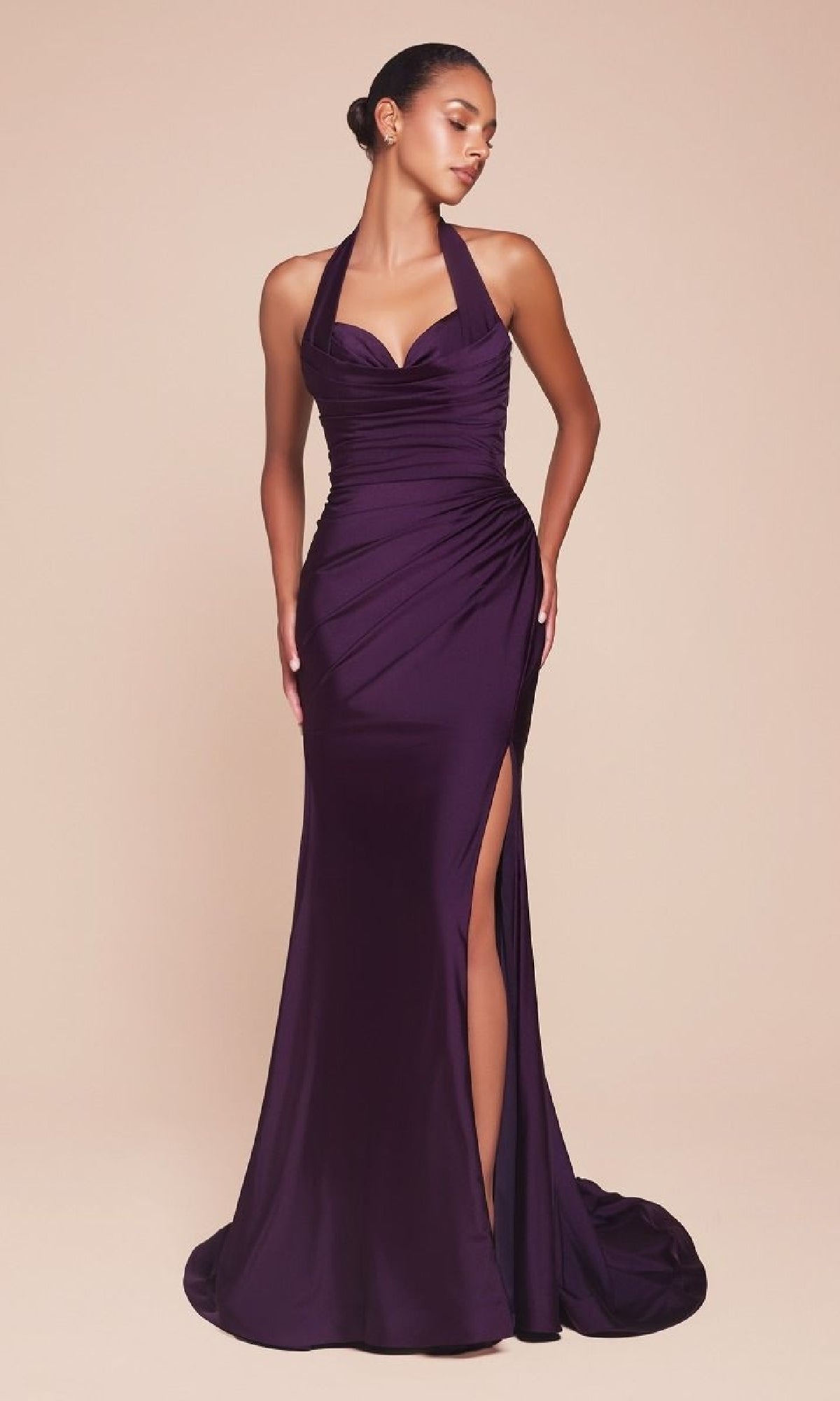 A woman wears the Classic Long Halter Prom Dress: CLCD796, a fitted, floor-length dark purple gown with a halter neckline and thigh-high slit, standing against a plain beige background.