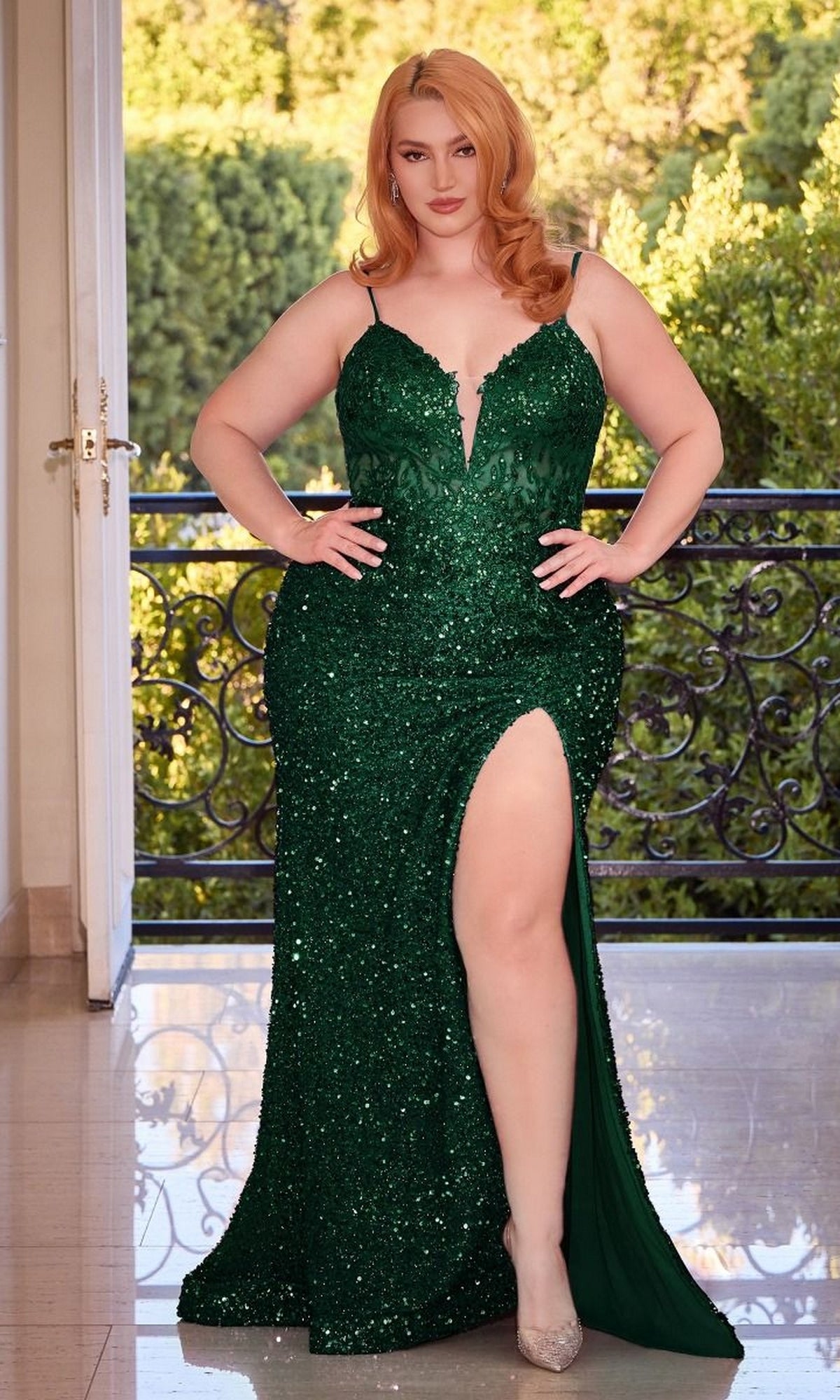 A woman in the V-Neck Plus-Size Long Sequin Prom Dress CD840C with a thigh-high slit stands indoors near an open door, greenery visible outside.
