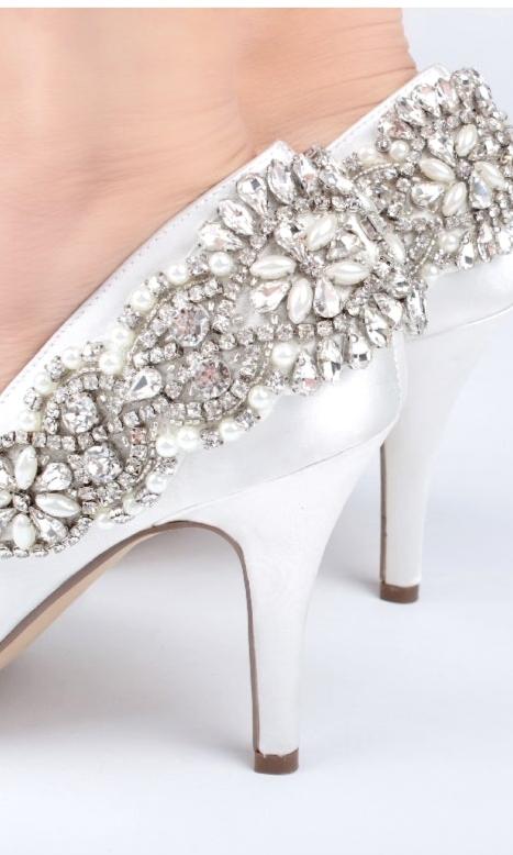 Close-up of a foot wearing Cynthia Ivory Prom Shoes: Paradox London P1809, featuring stiletto heels and an ornate pattern of pearls and rhinestones.