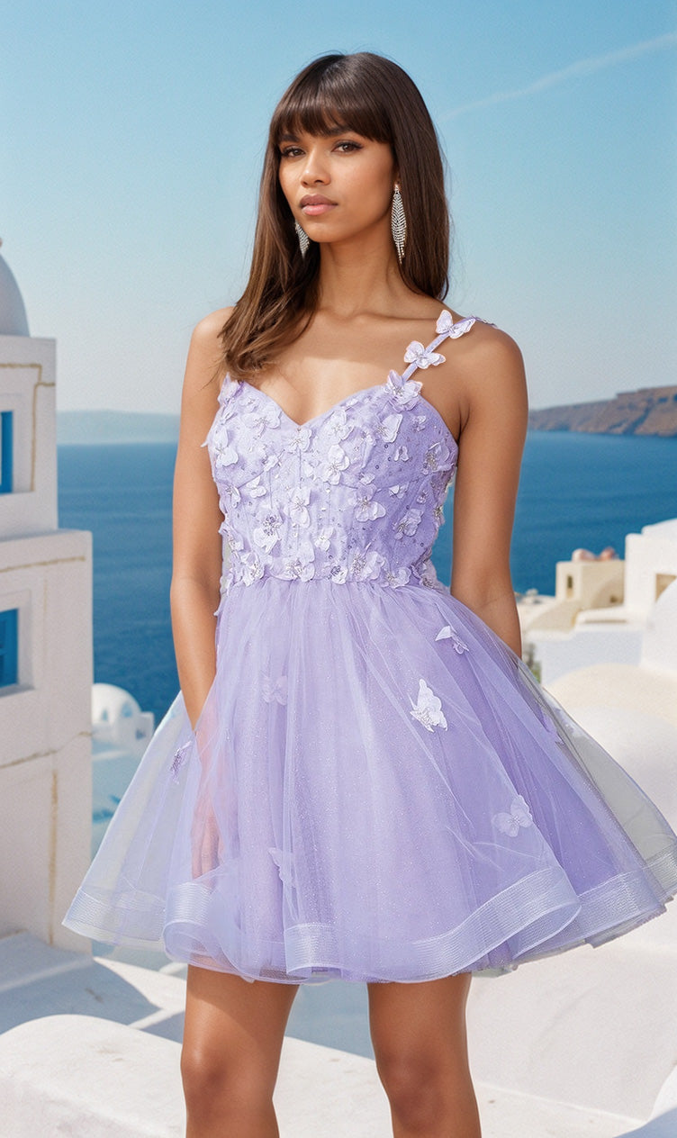 A woman poses outdoors by white buildings and blue sea, wearing the Lace-Up Short Butterfly Homecoming Dress 3369—a light purple, one-shoulder semi-formal dress adorned with delicate 3-D butterflies and floral appliqués.