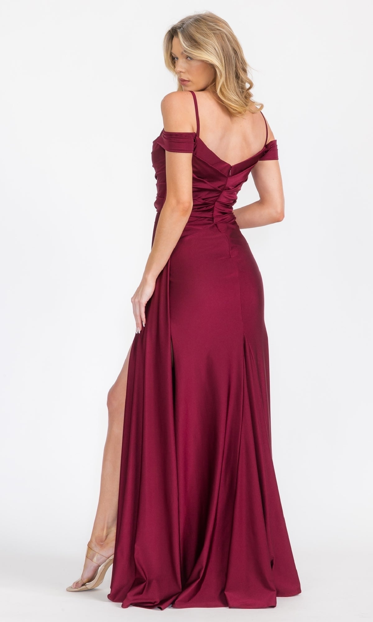 A woman in the Eureka EK117 Off-Shoulder Long Formal Dress, featuring a floor-length silhouette and thigh-high slit, stands facing away, glancing over her shoulder.