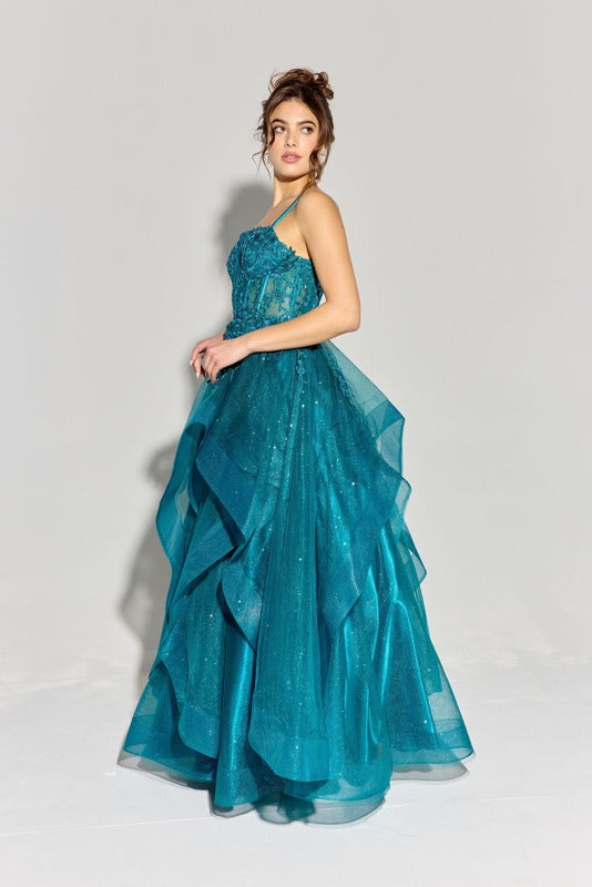 A woman wearing the Eureka EK157 long prom dress—a teal, floor-length gown with a glitter tulle skirt and spaghetti straps—stands against a plain light background.