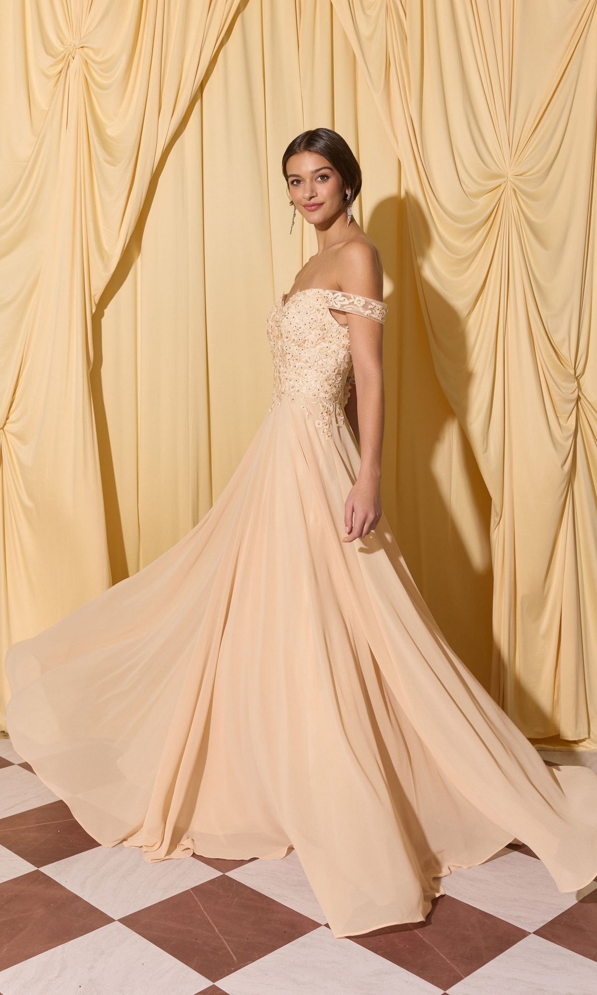 A woman poses in front of yellow curtains on a checkered floor wearing the Long Prom Dress: Eureka EK211, featuring an off-the-shoulder lace applique bodice.
