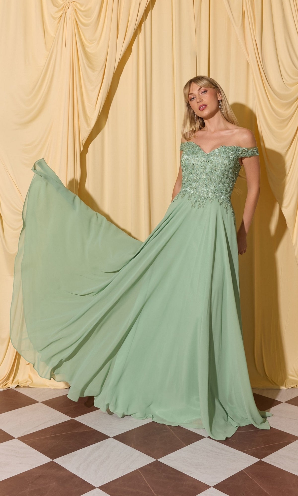 A woman in the Long Prom Dress: Eureka EK211 in sage poses before yellow curtains on a brown and white checkered floor.