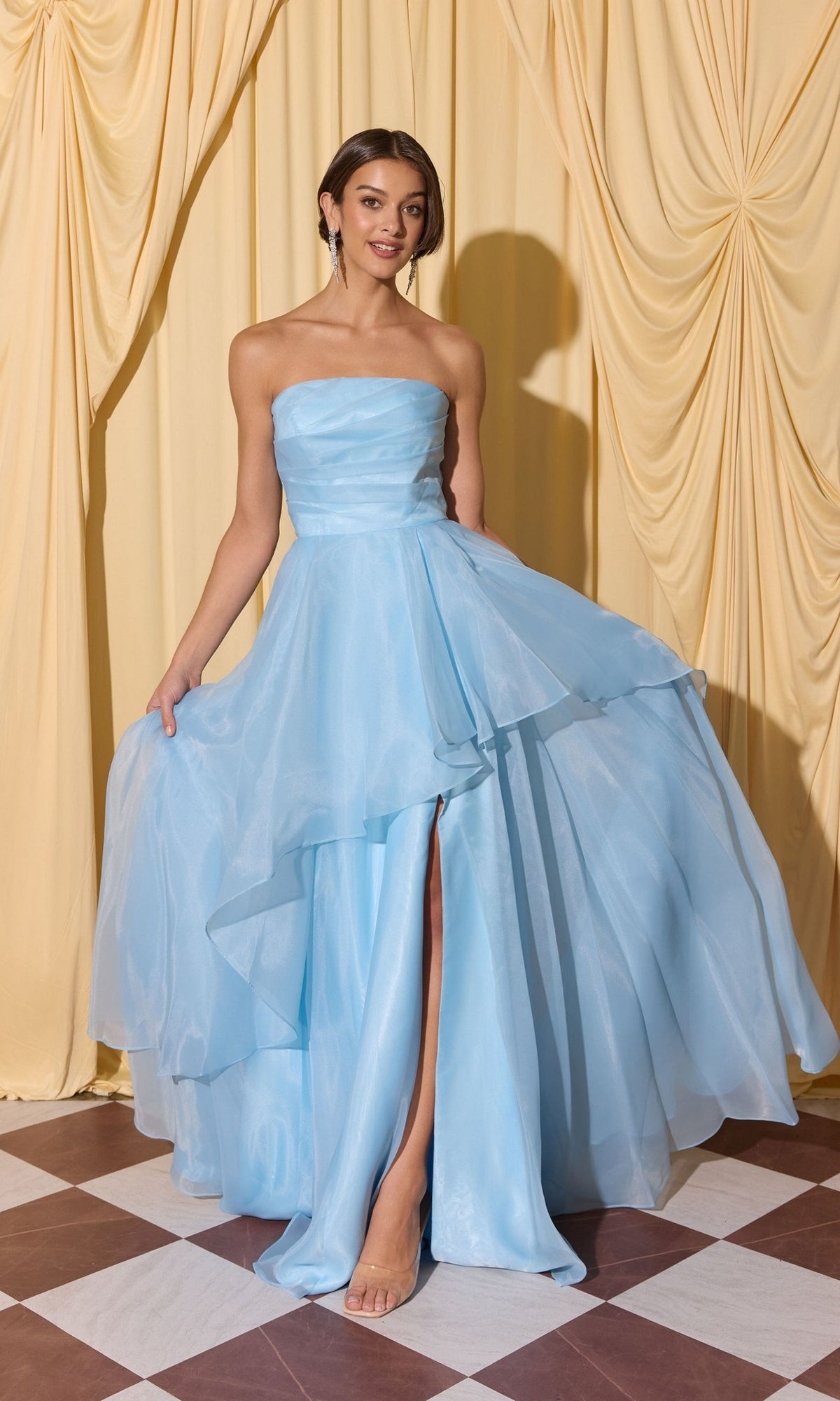 Woman in the Long Prom Dress: Eureka EK216 with a strapless a-line skirt and high slit, standing on a checkered floor before yellow curtains.