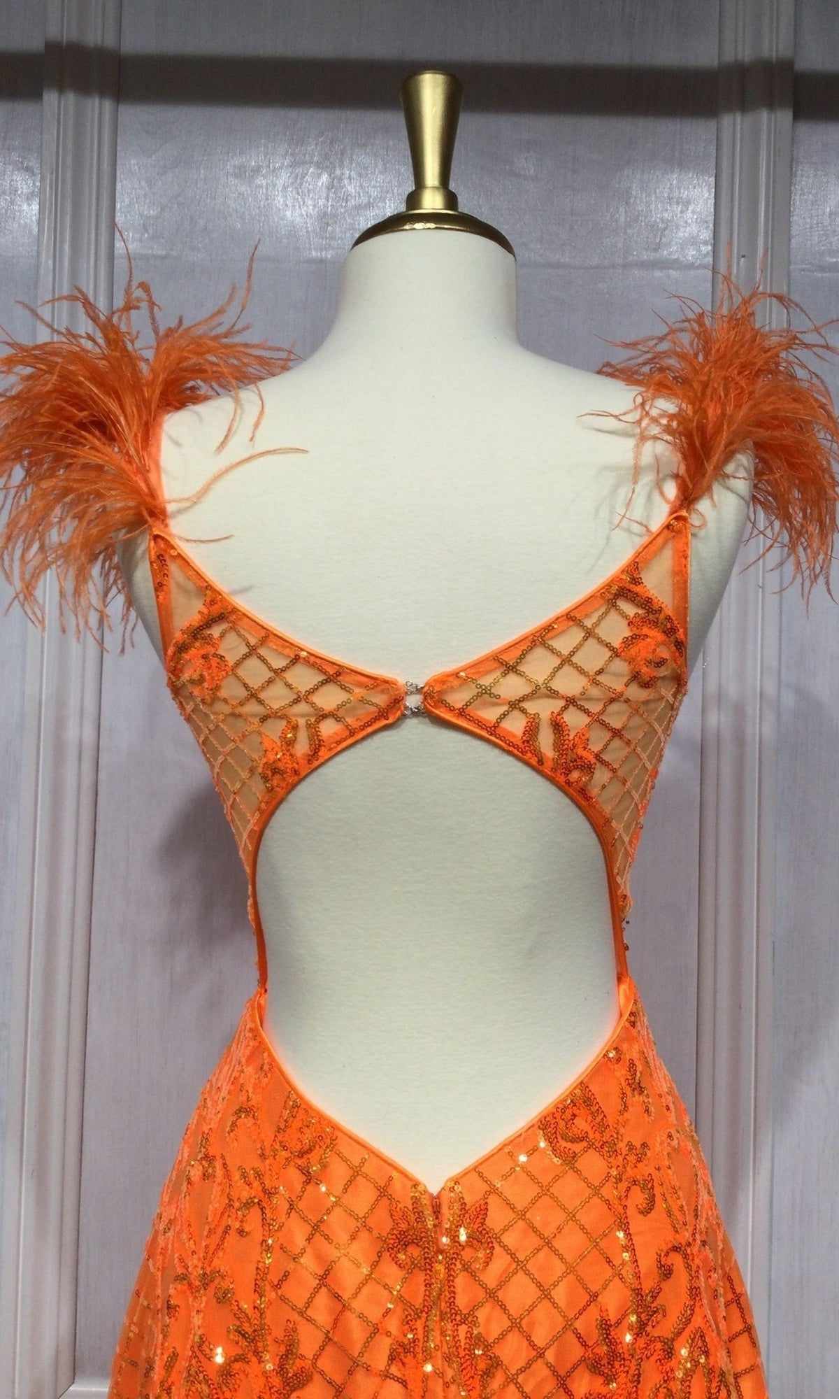 A mannequin showcases the Feathered Neon Orange Long Sequin Prom Dress KV1076, featuring dazzling sequins in a grid pattern, feathered shoulder straps, and a low open back.