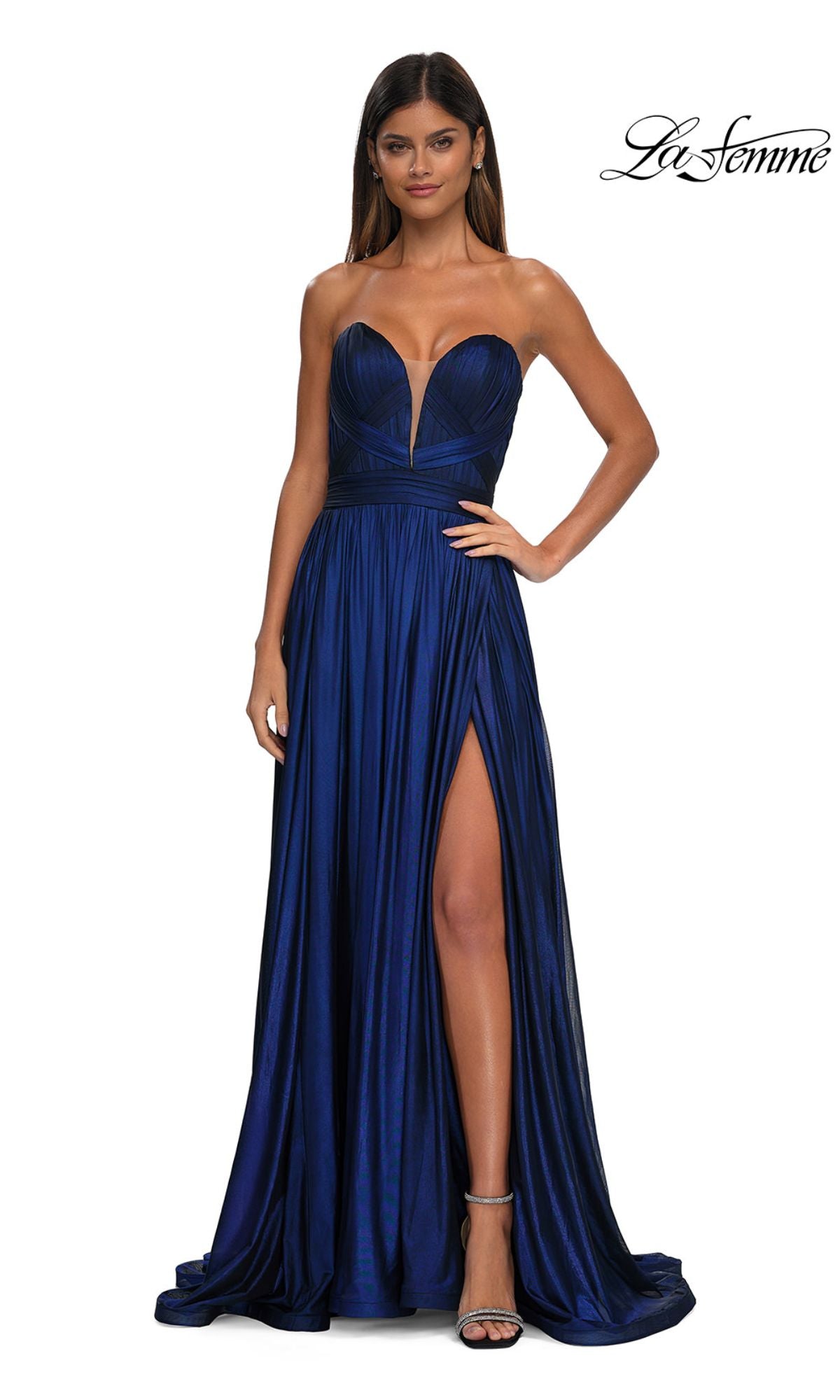 A woman wears the Strapless Long Metallic Prom Gown: La Femme 32988 in deep blue, featuring a sweetheart neckline and thigh-high slit, standing against a plain background.