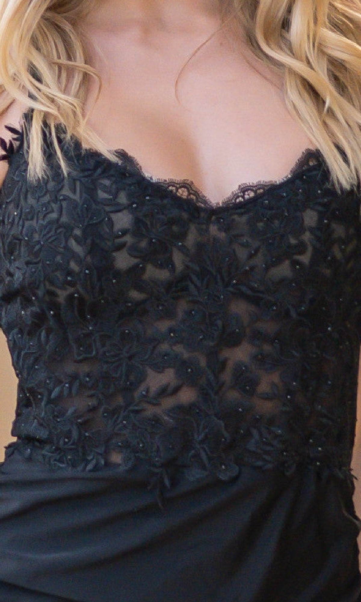 A close-up of a person wearing the Velvi Rylie Lace-Bodice Tight Long Prom Gown—a black formal dress featuring floral lace patterns and sheer bodice detailing.
